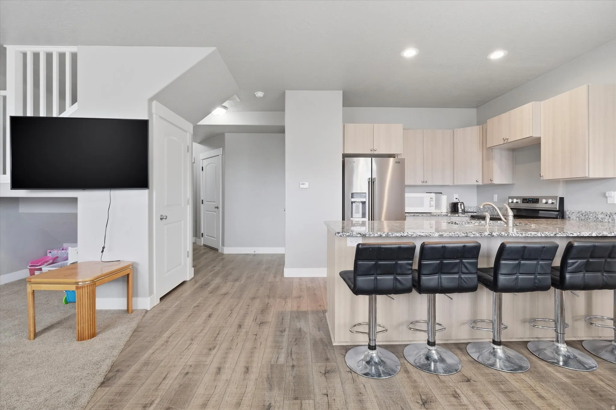 Kitchen featuring light wood finish cabinets, light stone countertops, a peninsula, stainless steel appliances, and recessed lighting