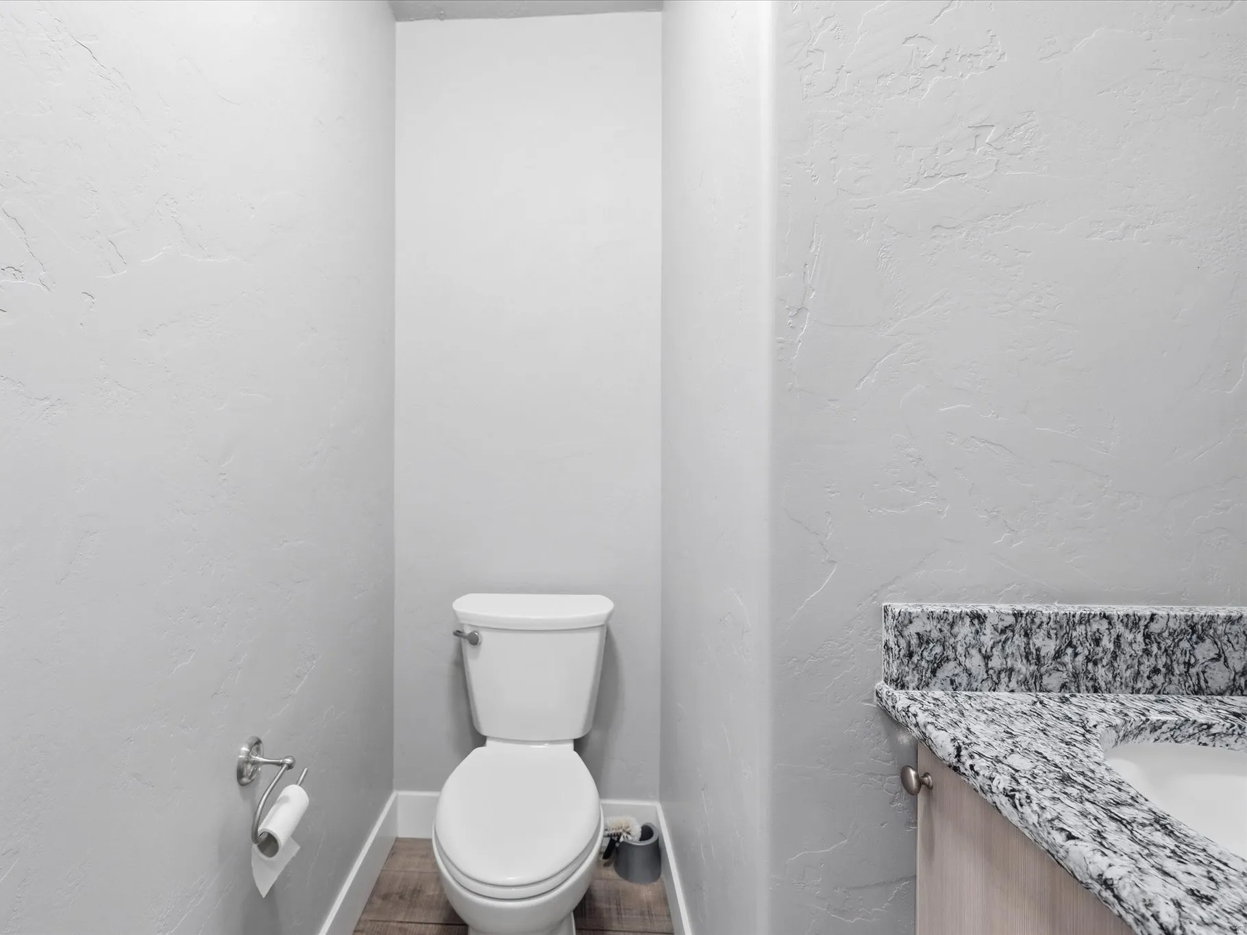Half bathroom featuring a textured wall and vanity