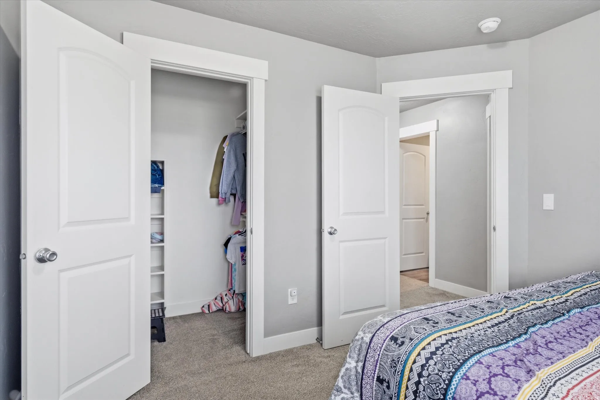Bedroom featuring light colored carpet and a spacious closet