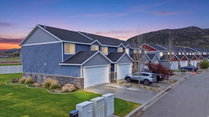 Traditional home featuring concrete driveway, a mountain view, an attached garage, roof with shingles, and a lawn