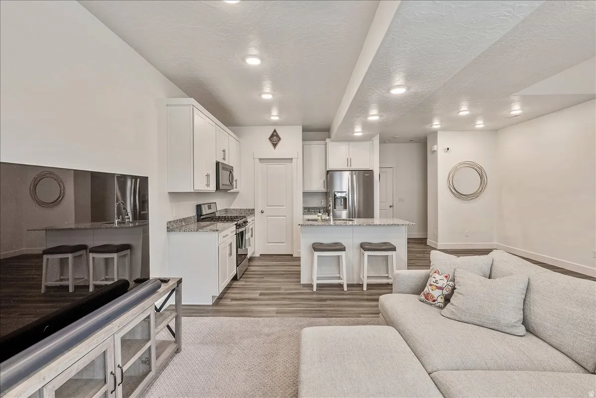 Living room with light wood finished floors, recessed lighting, and a textured ceiling