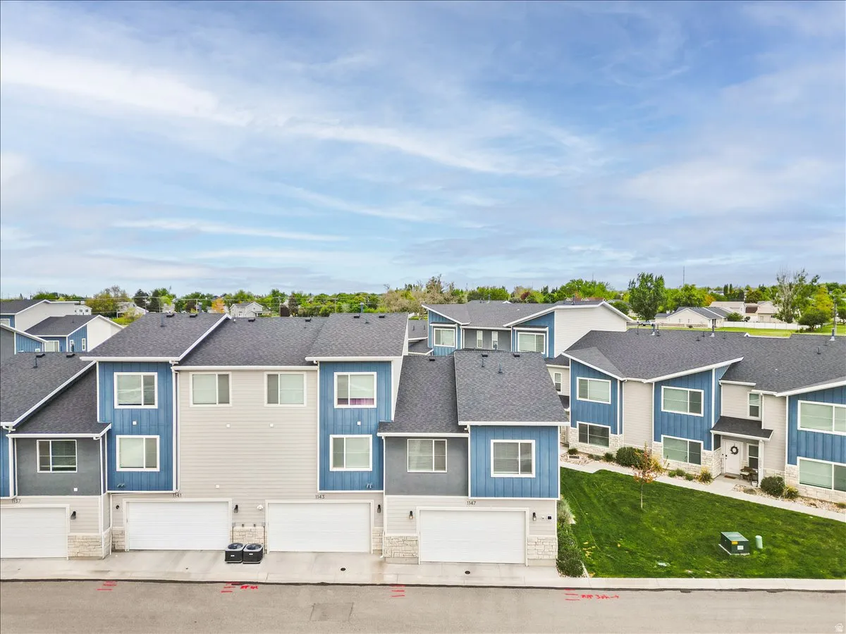 Traditional-style house featuring an attached garage, a residential view, roof with shingles, stone siding, and board and batten siding