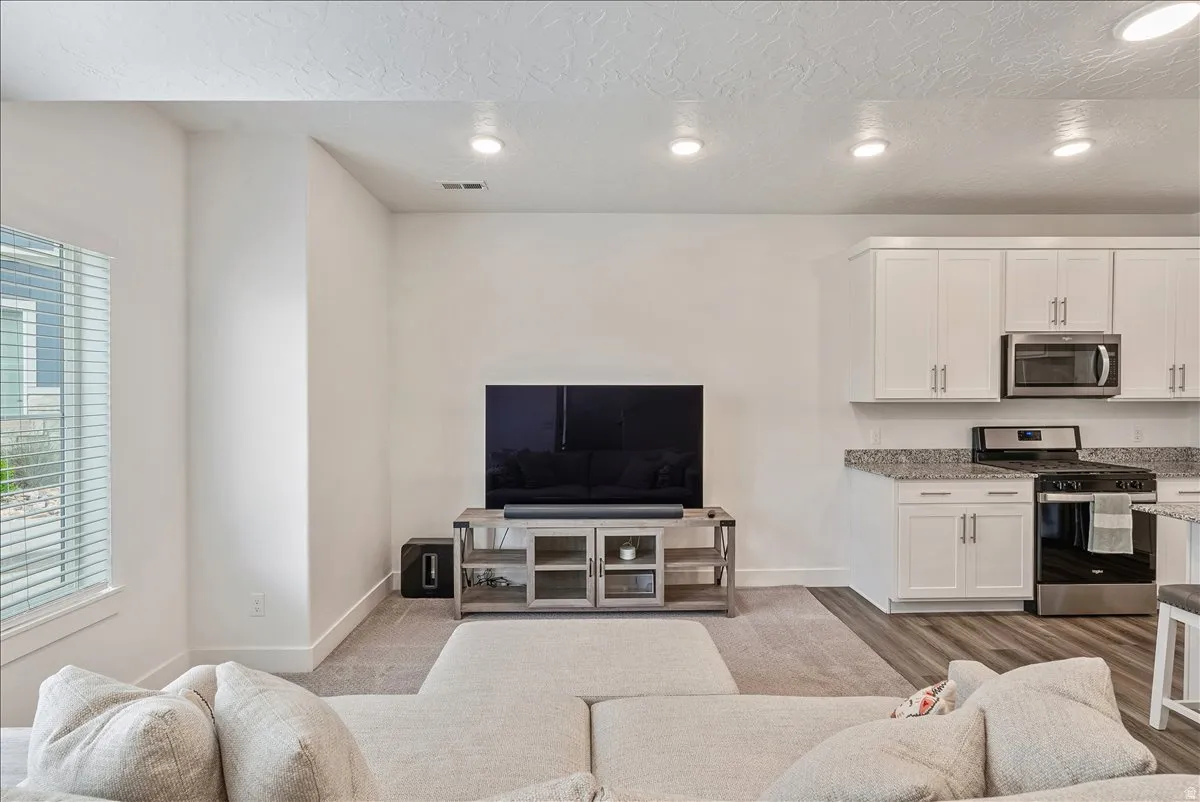 Living area with recessed lighting, a textured ceiling, and light wood finished floors