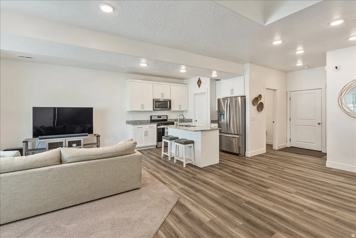 Living room with dark wood-type flooring, recessed lighting, and a textured ceiling