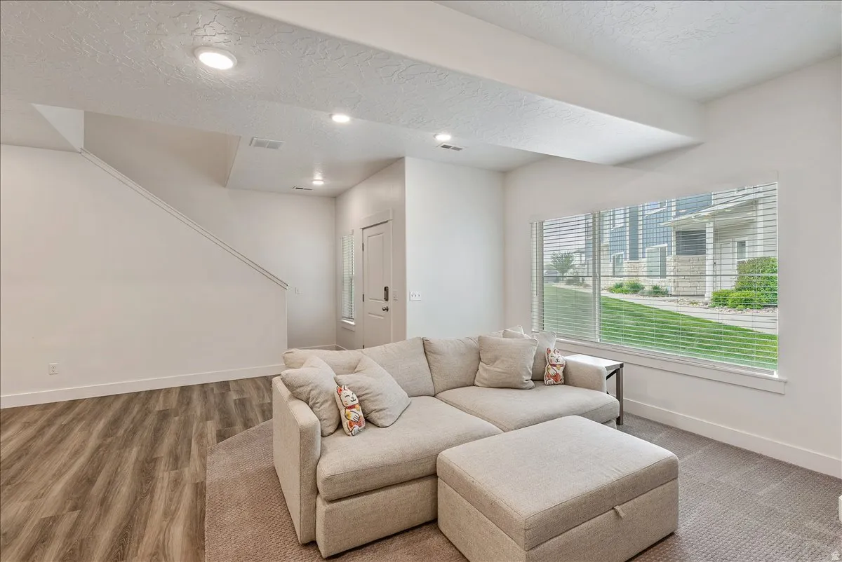 Living room with a textured ceiling, recessed lighting, and wood finished floors