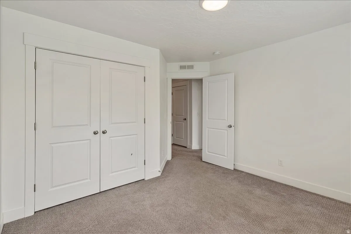 Unfurnished bedroom with carpet, a closet, and a textured ceiling