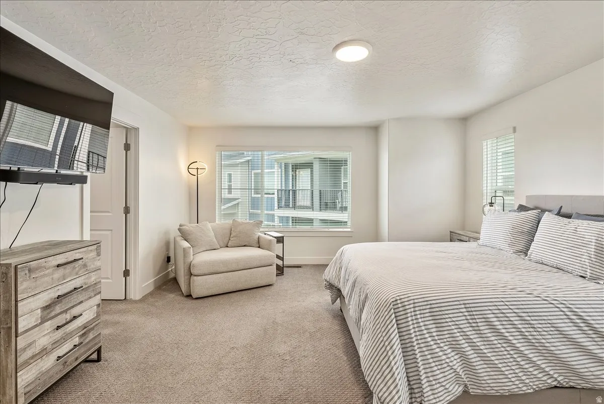 Bedroom featuring light carpet and a textured ceiling