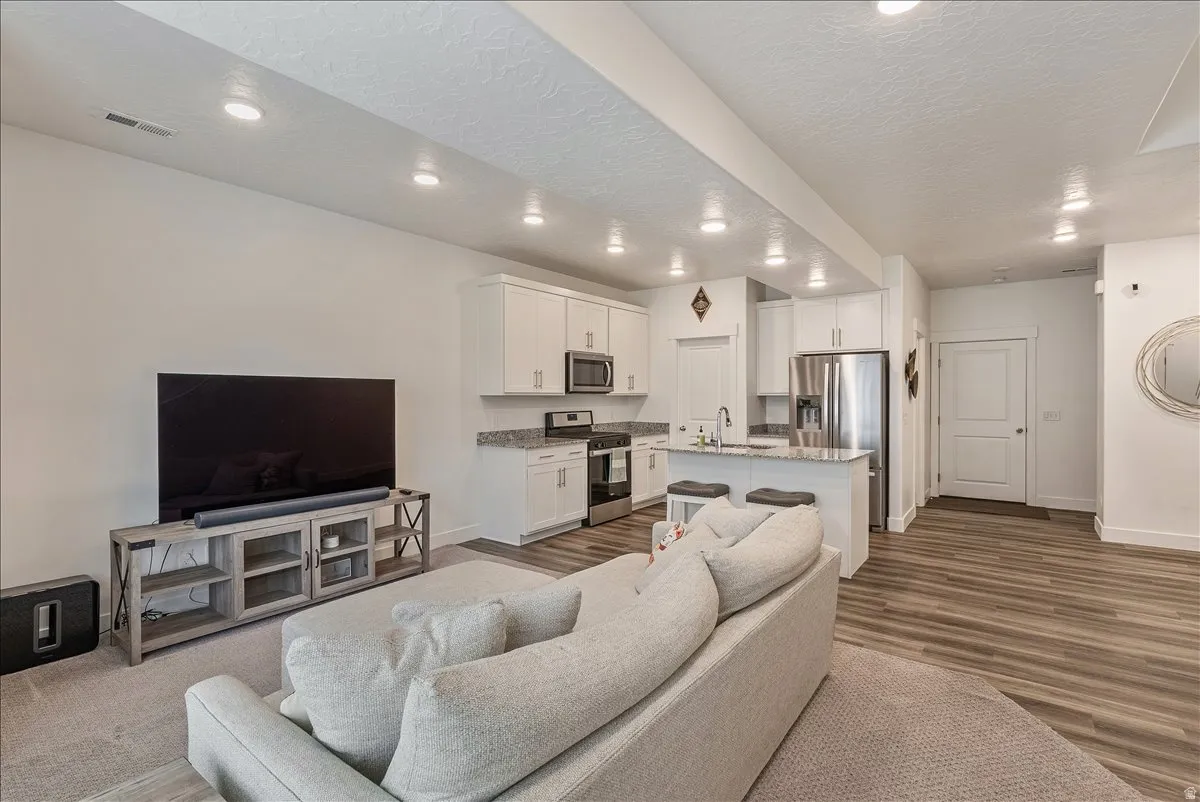 Living room featuring dark wood-style flooring, a textured ceiling, and recessed lighting