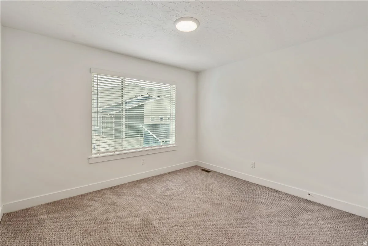 Empty room featuring light colored carpet and a textured ceiling