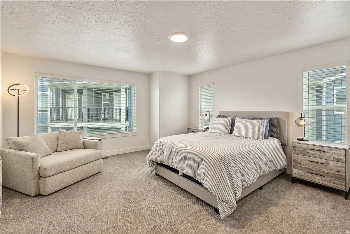 Carpeted bedroom featuring a textured ceiling and baseboards