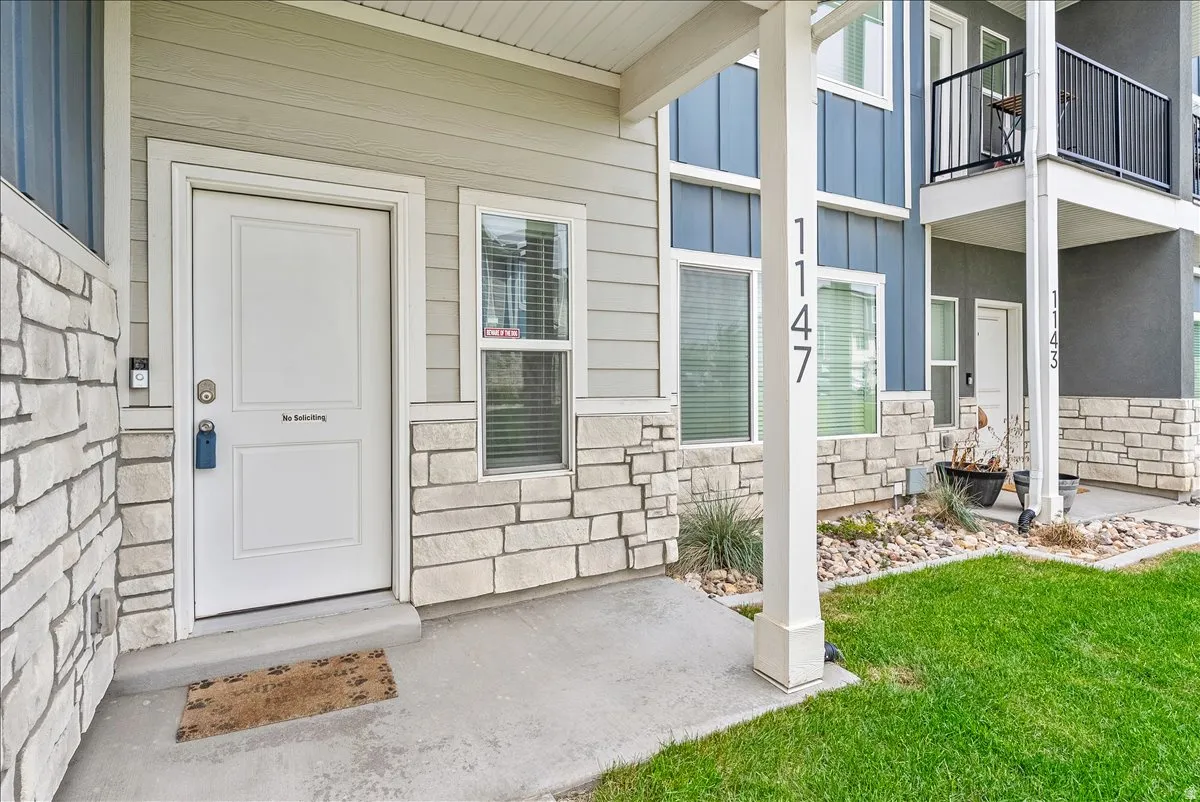 Entrance to property featuring stone siding, a porch, board and batten siding, and a yard