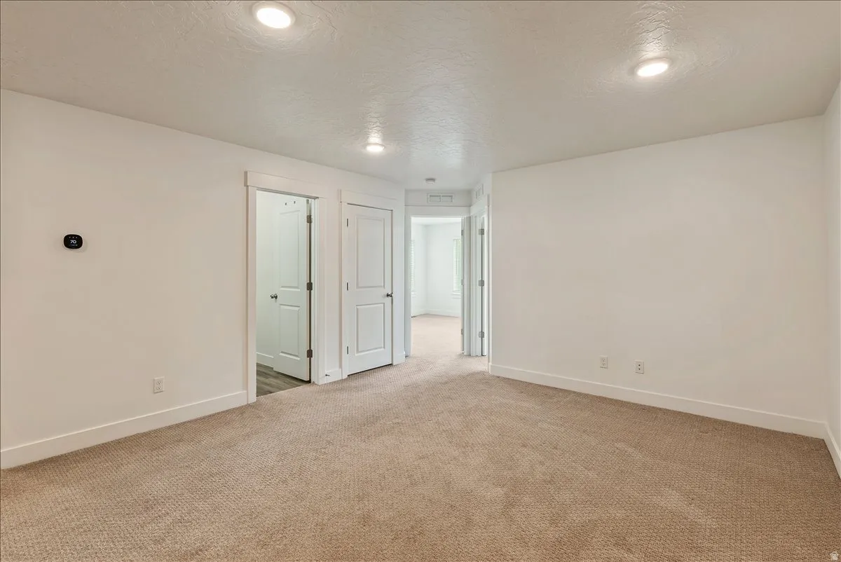 Empty room with a textured ceiling, light colored carpet, and recessed lighting