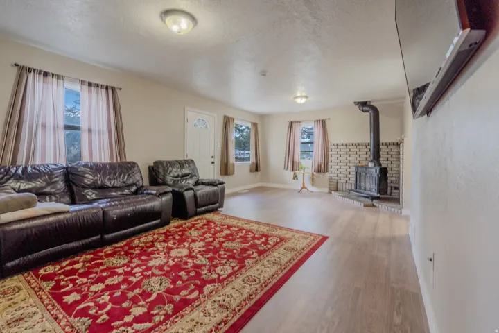 Wood-finish flooring, recessed lighting, and a wood-burning stove with a brick surround