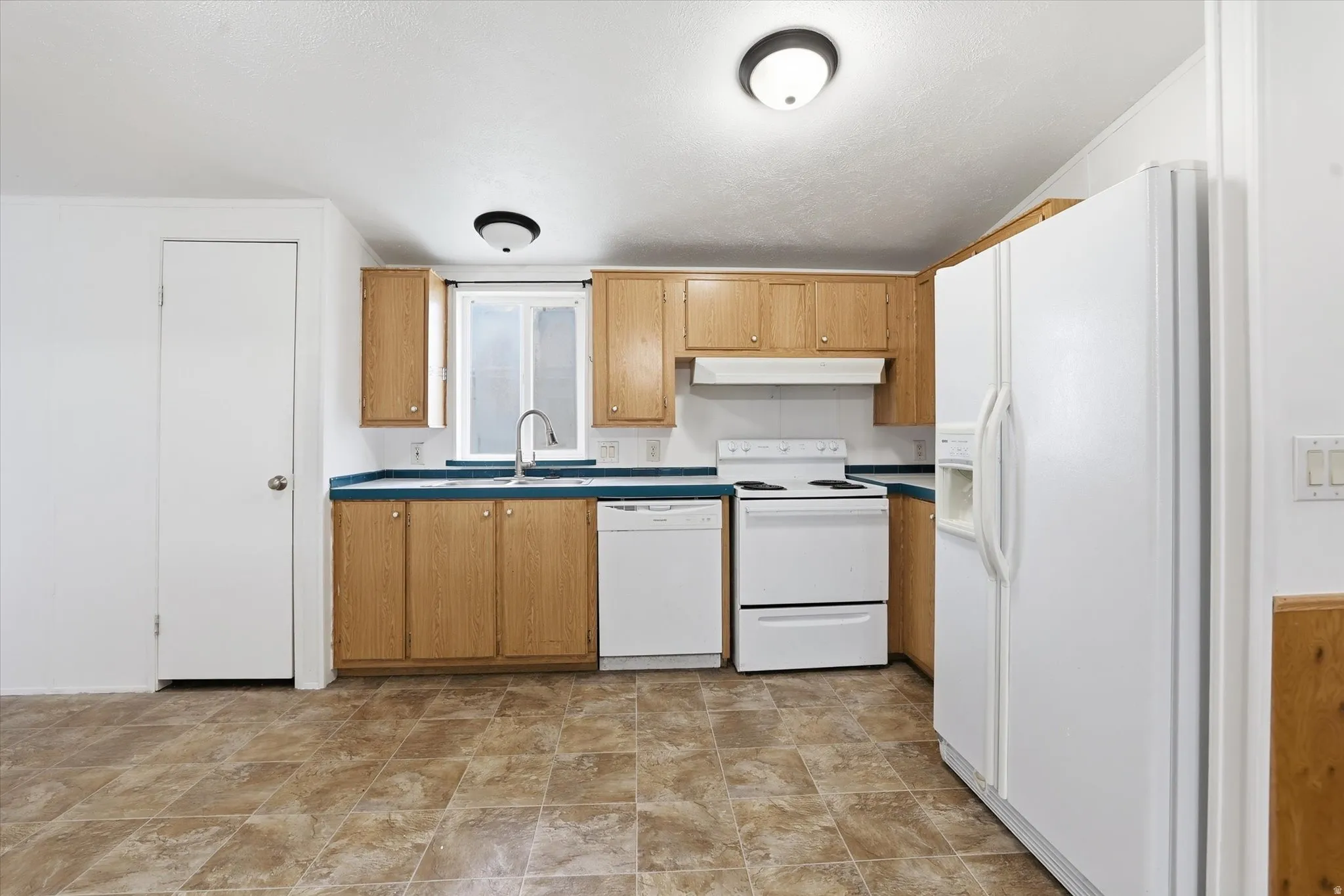 Kitchen with white appliances and stone finish flooring