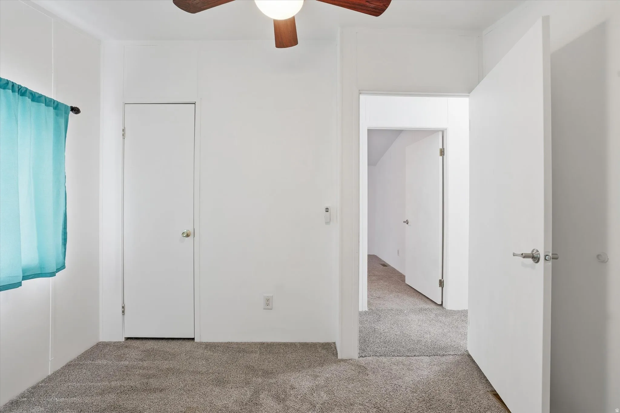 Unfurnished bedroom featuring light colored carpet and ceiling fan