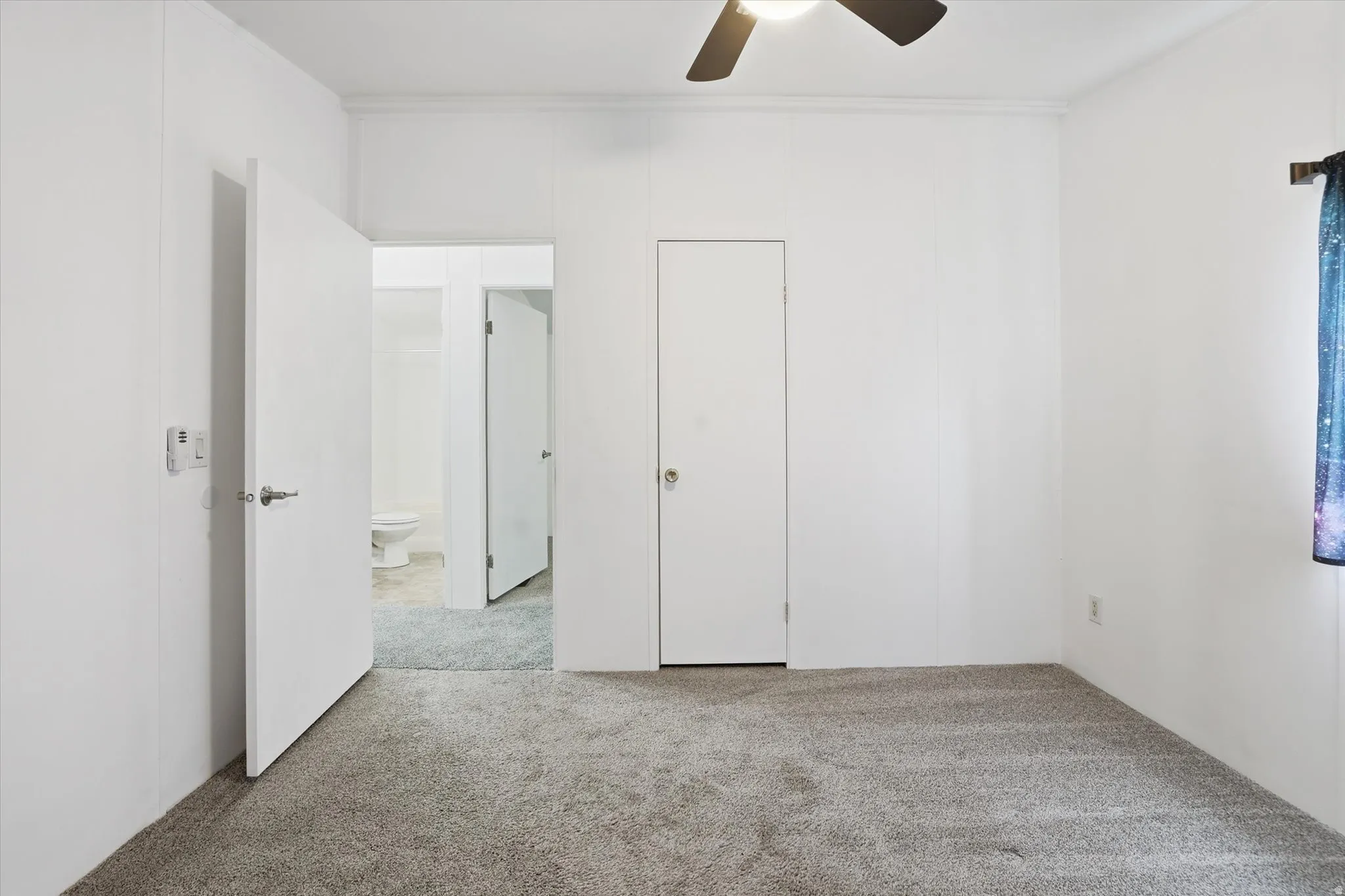 Unfurnished bedroom featuring light carpet and a ceiling fan