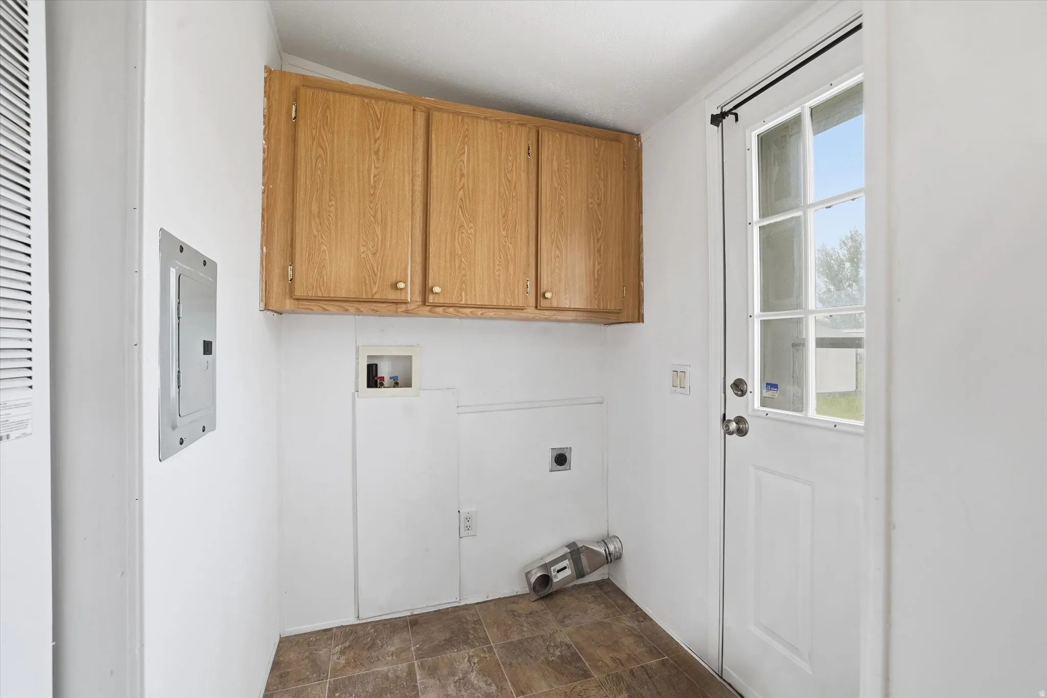 Laundry area featuring cabinet space, stone finish flooring, electric dryer hookup, washer hookup, and electric panel