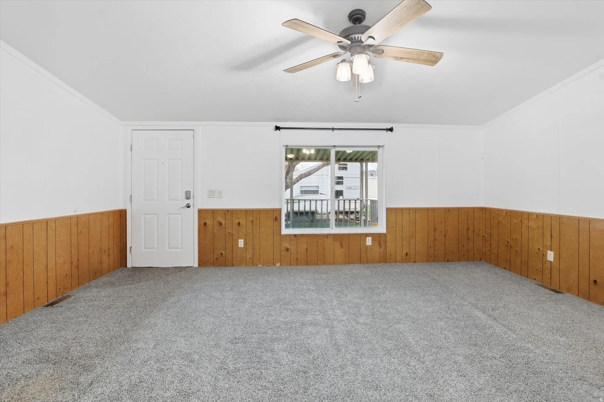 Carpeted spare room with ornamental molding, wooden walls, a wainscoted wall, and a ceiling fan