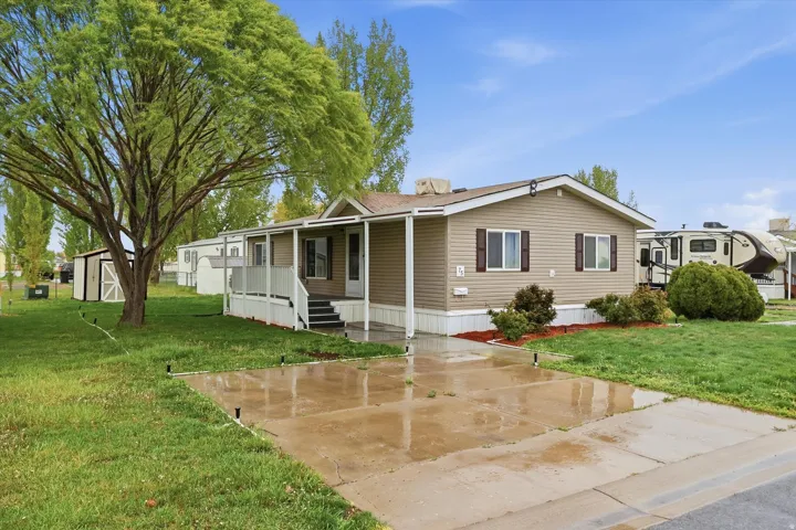 Manufactured / mobile home with a front lawn, a porch, and a storage shed