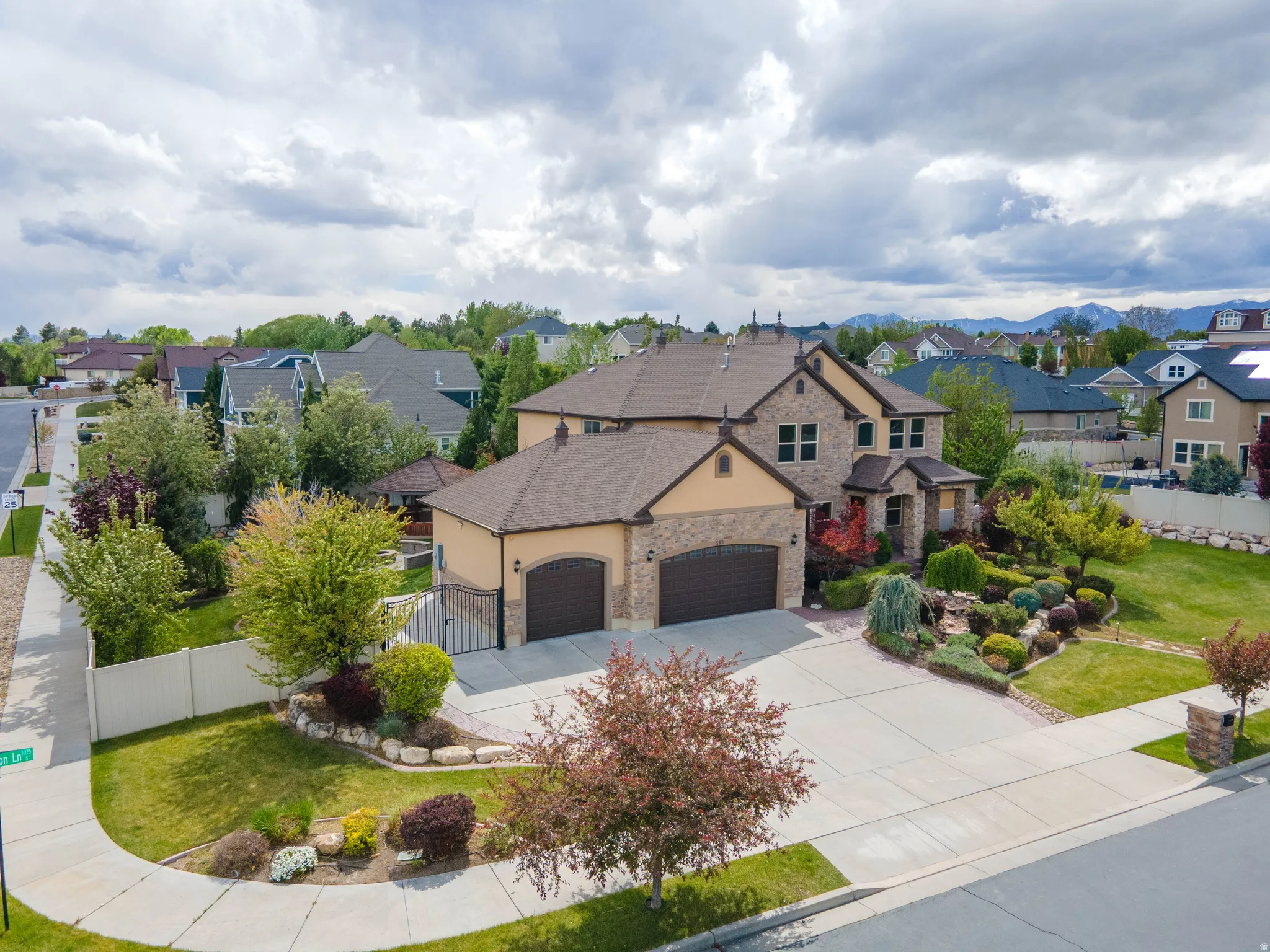 View of front of home featuring stone siding, a residential view, a garage, driveway, and stucco siding