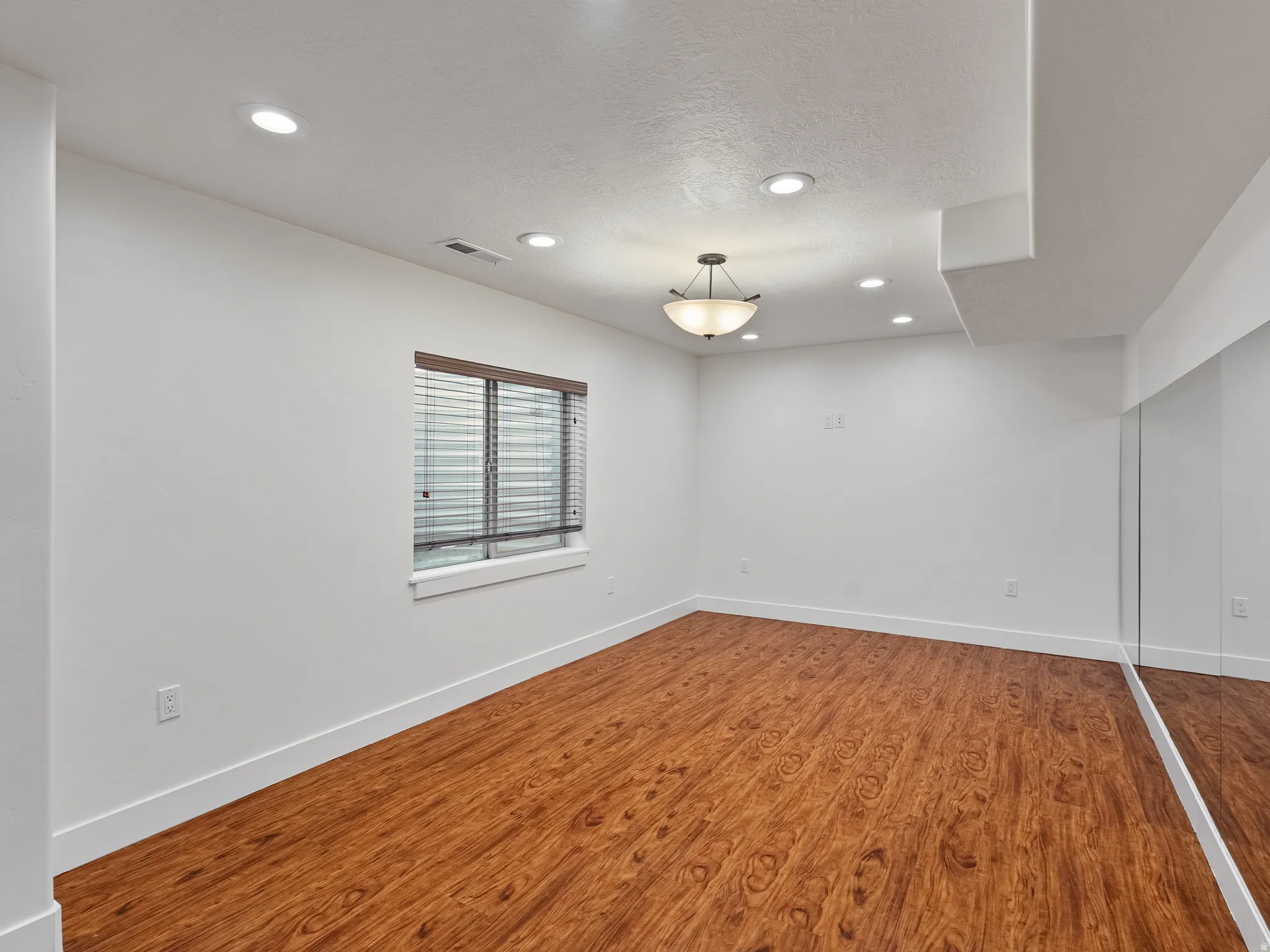 Unfurnished room with wood finished floors, recessed lighting, and a textured ceiling