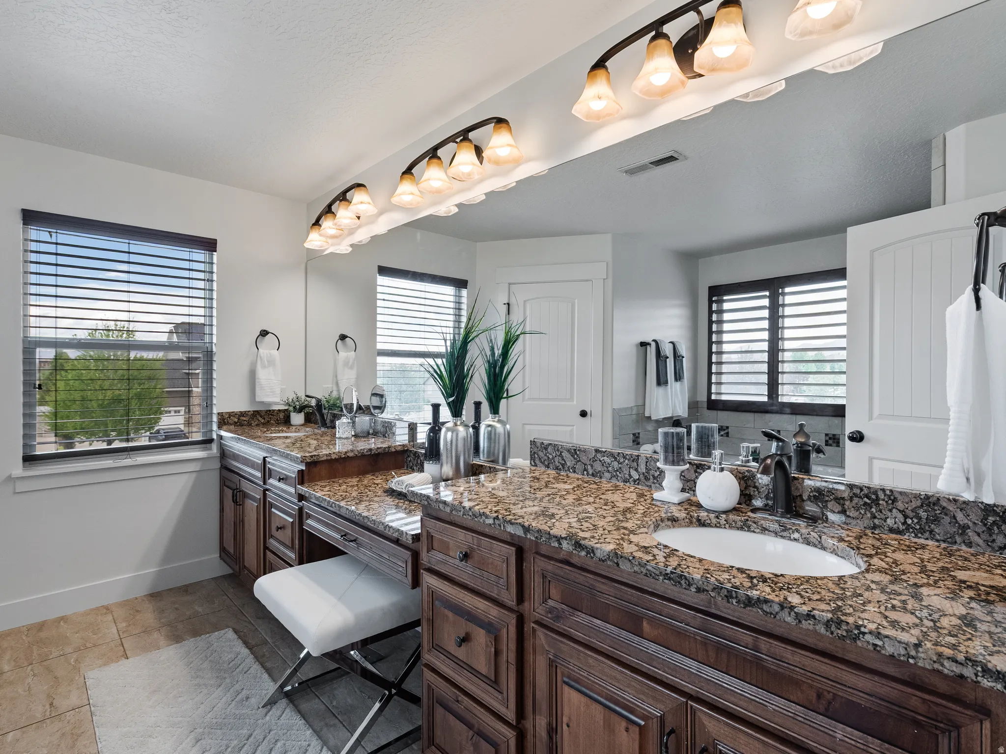 Full bath featuring vanity, healthy amount of natural light, and light tile patterned floors