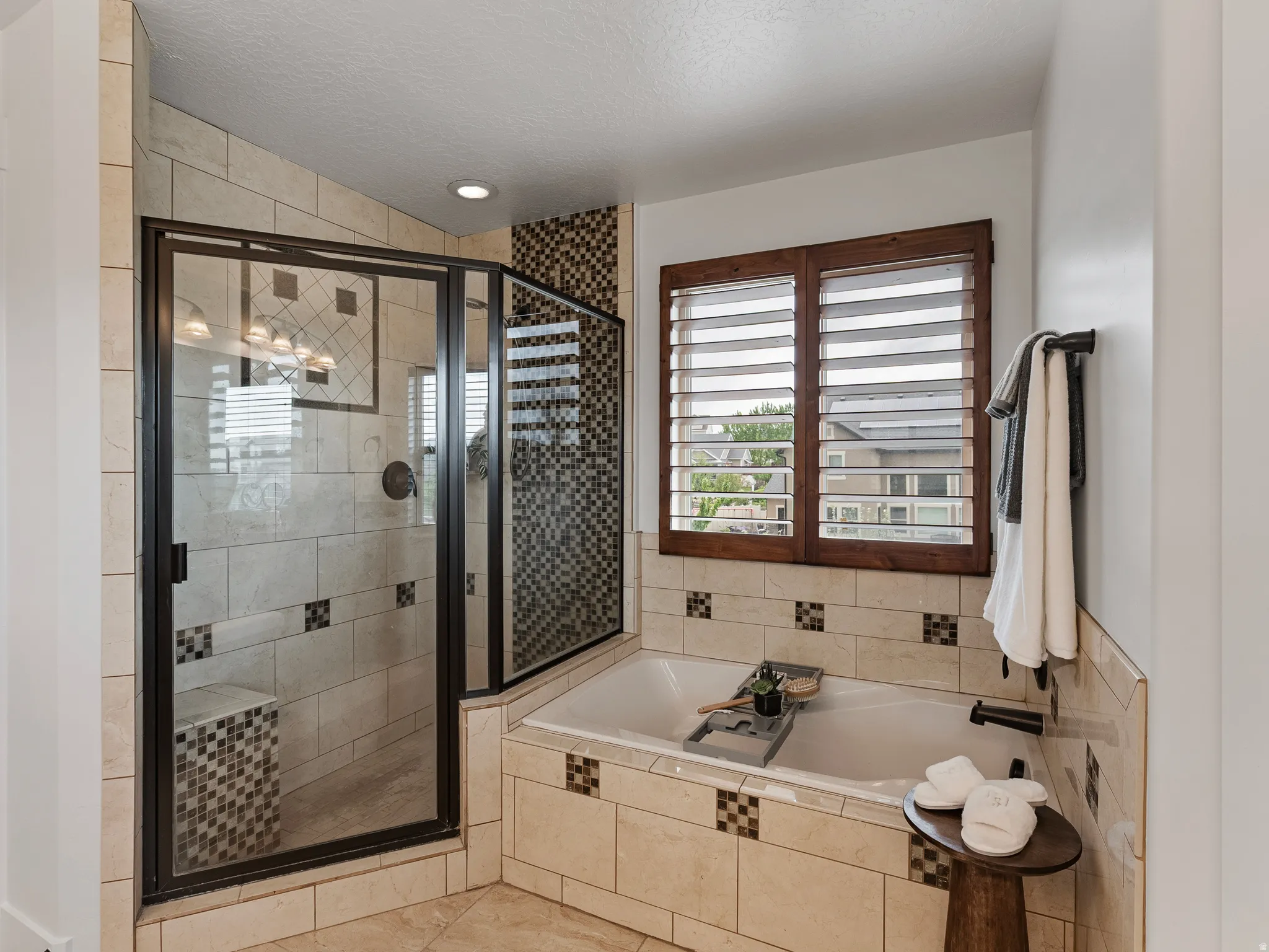Full bathroom featuring a stall shower, a garden tub, and a textured ceiling