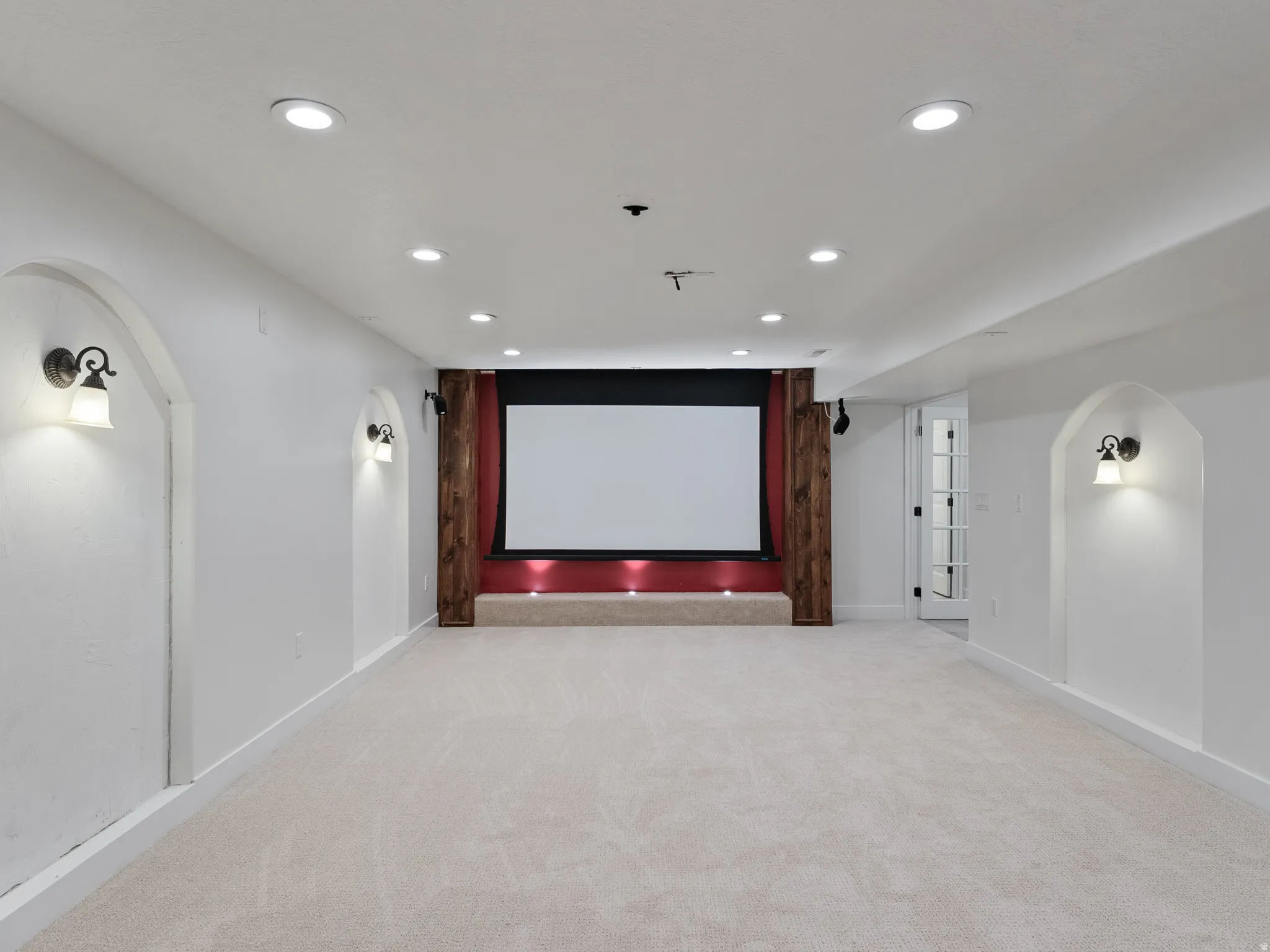 Home theater room featuring arched walkways, light colored carpet, and recessed lighting