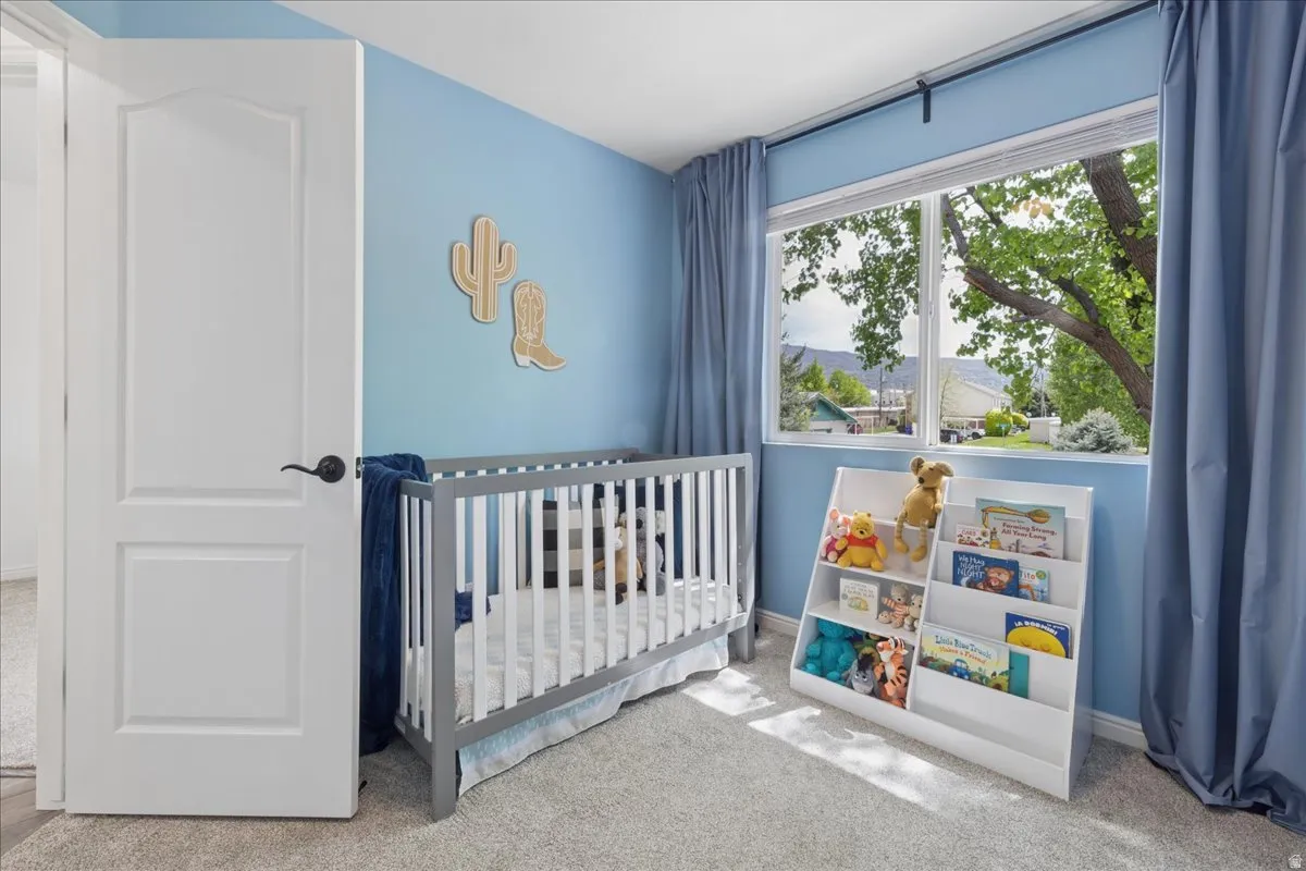 Bedroom featuring light carpet and a nursery area