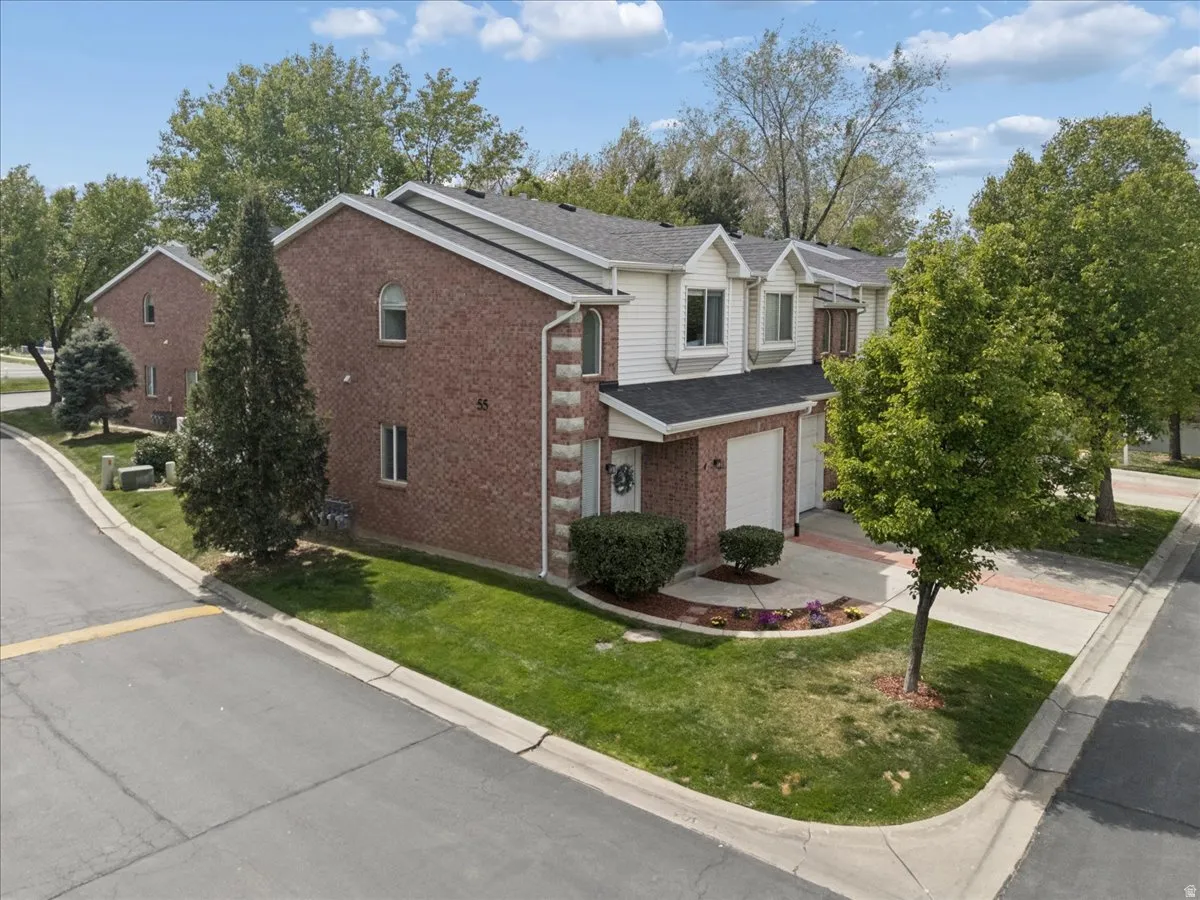 Traditional home with brick siding, a garage, concrete driveway, a front yard, and a porch