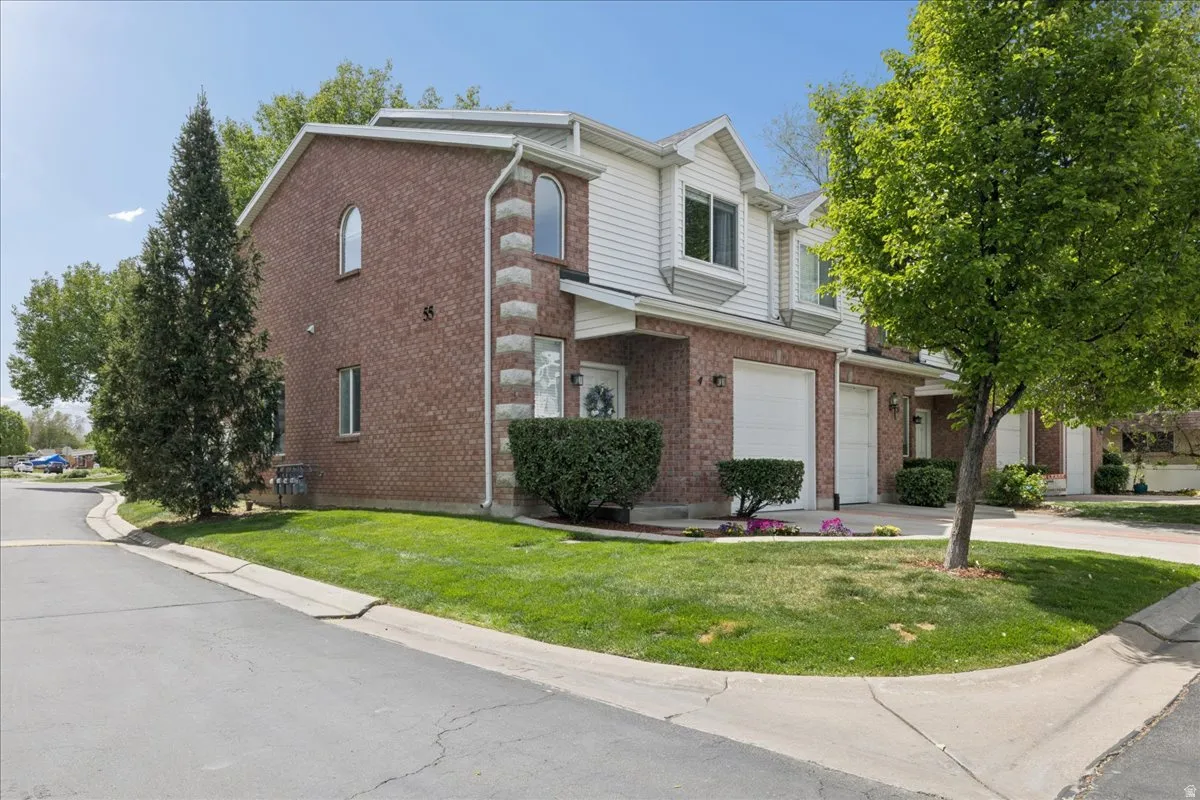 Traditional-style house featuring an attached garage, brick siding, driveway, and a front lawn