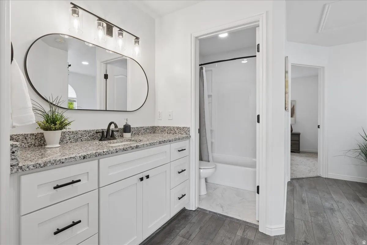 Full bathroom with dark wood-style flooring, vanity, shower / bath combo, and recessed lighting