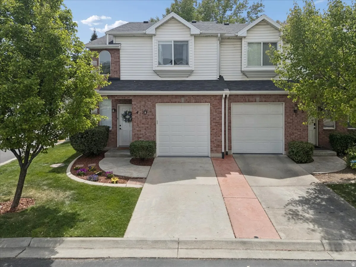 Traditional-style house featuring concrete driveway, a garage, brick siding, and a shingled roof
