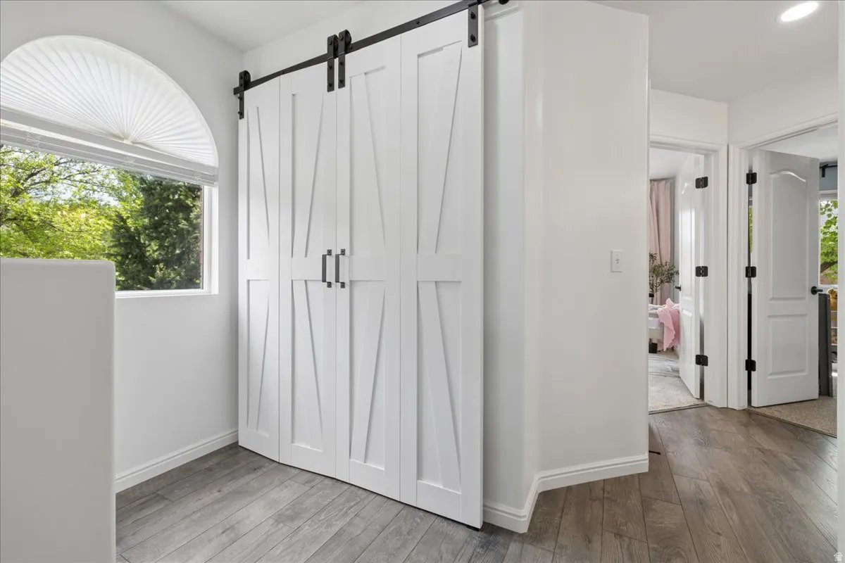 Unfurnished bedroom with a barn door and light wood-style floors