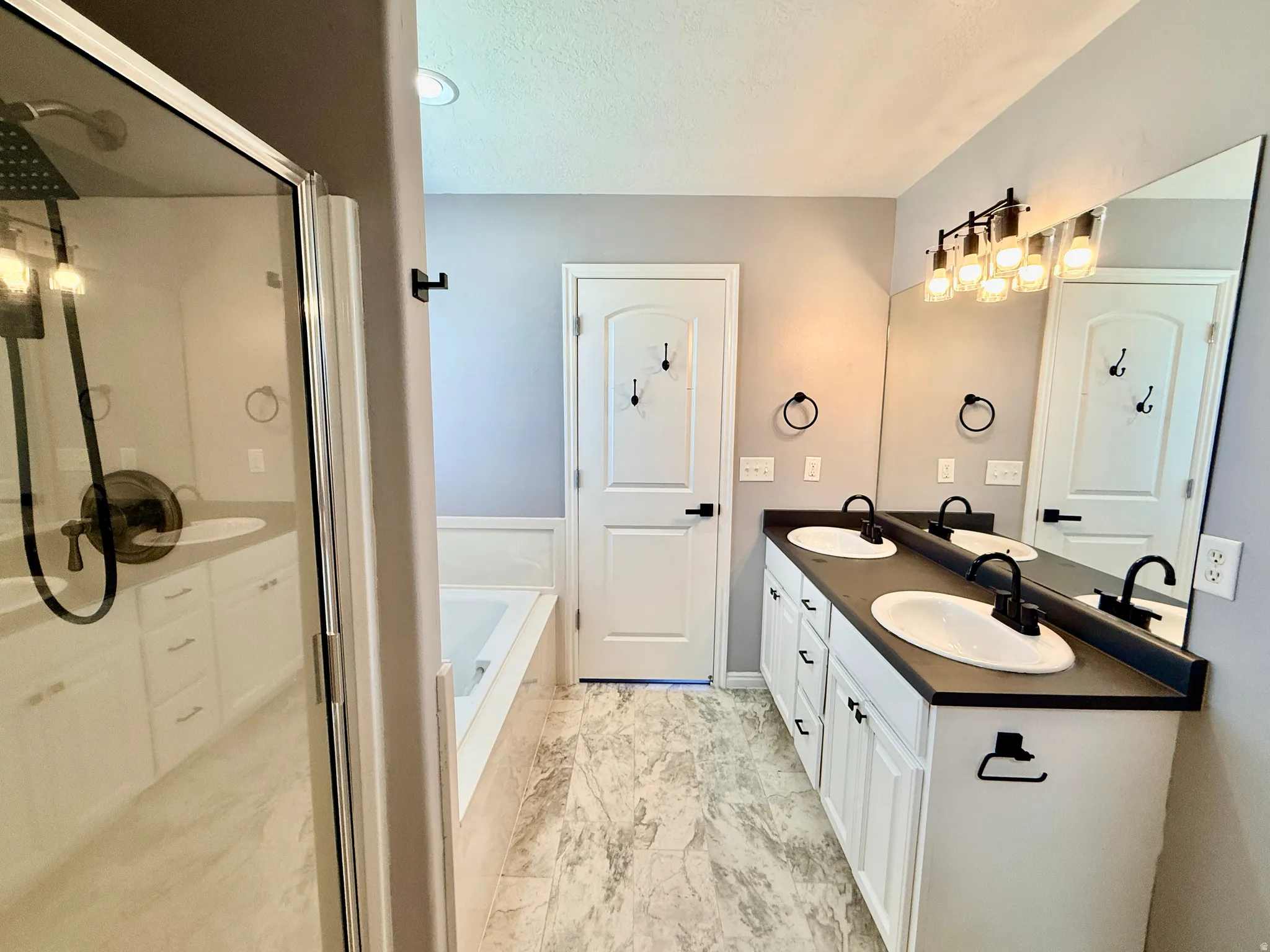 Bathroom featuring a dual vanity with white cabinetry and black countertops