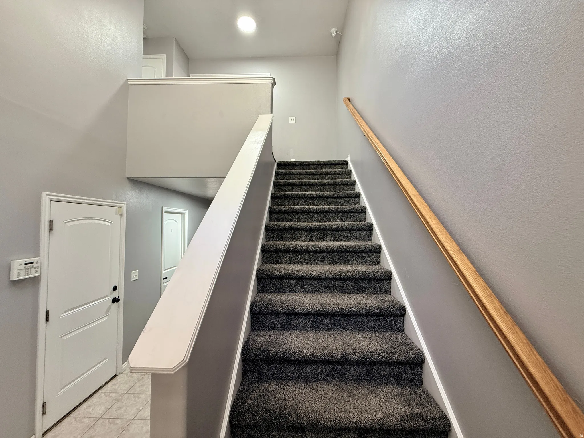 Carpeted staircase with a wood handrail and painted balustrade