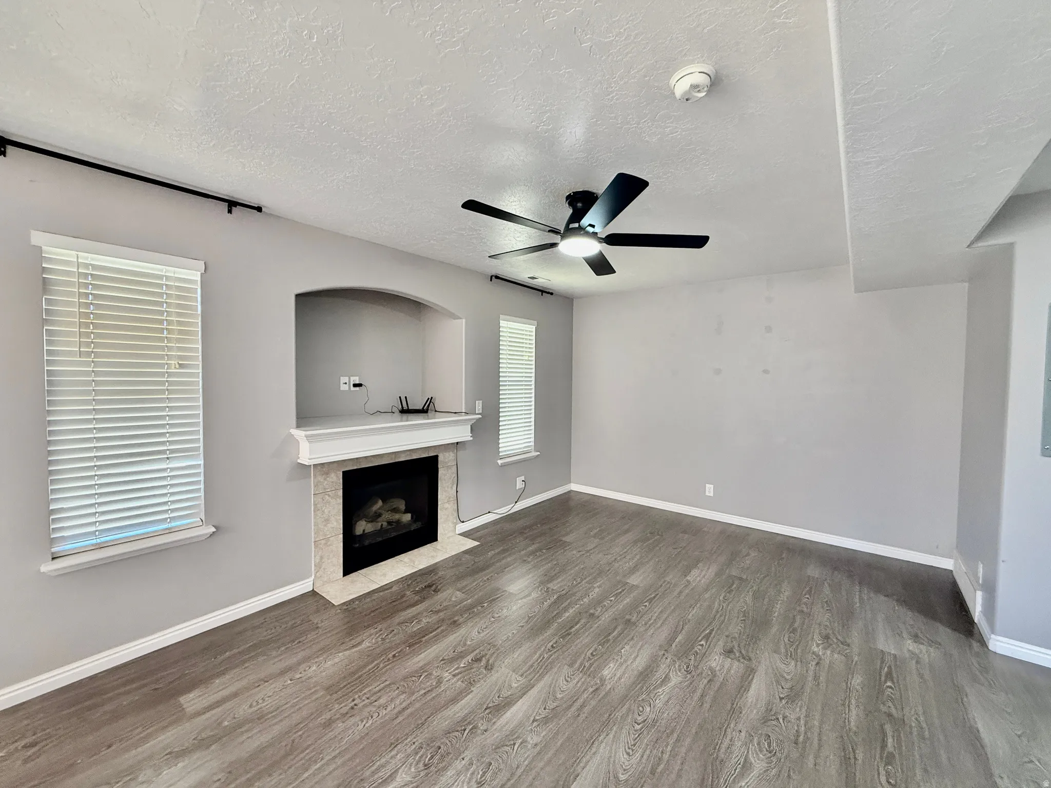 Living space featuring a tiled fireplace with a mantel, an arched built-in niche, and wood-finish flooring