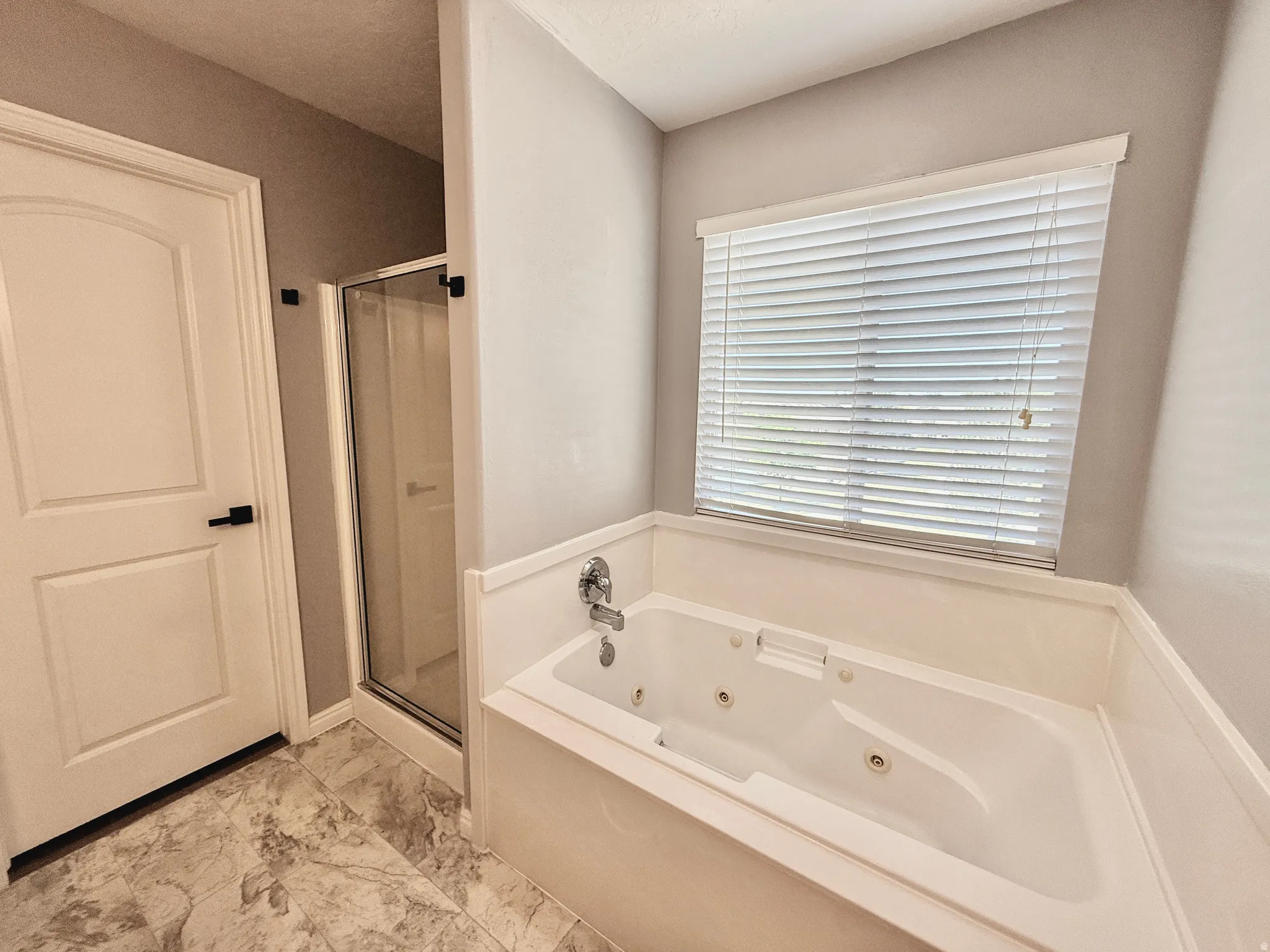 Soaking tub with integrated jets, chrome fixtures, and a white paneled skirt