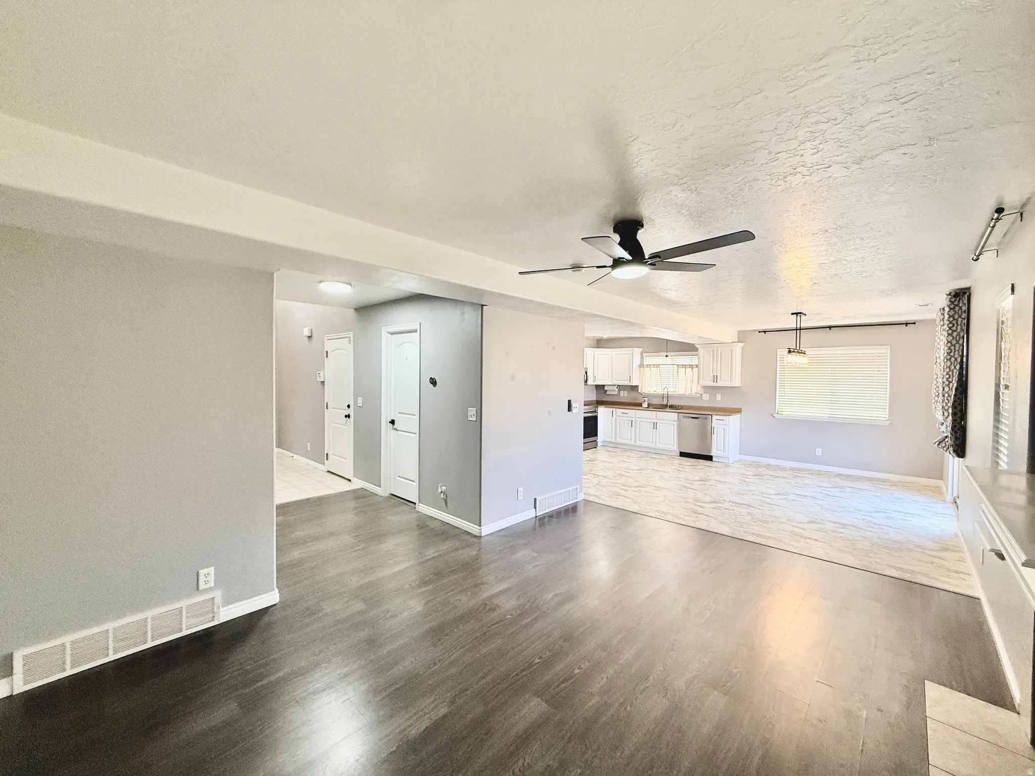 Spacious room featuring dark wood-finish flooring, a modern ceiling fan, and light gray wall paint
