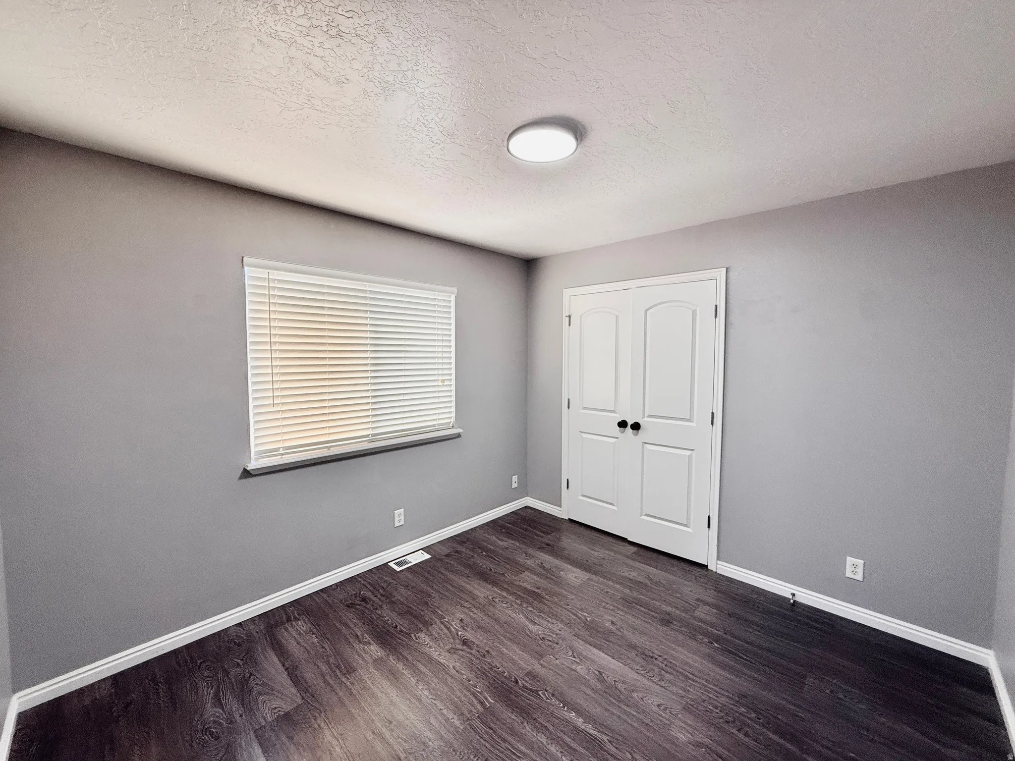 Room featuring wood-finish flooring, neutral gray wall tones, and white trim