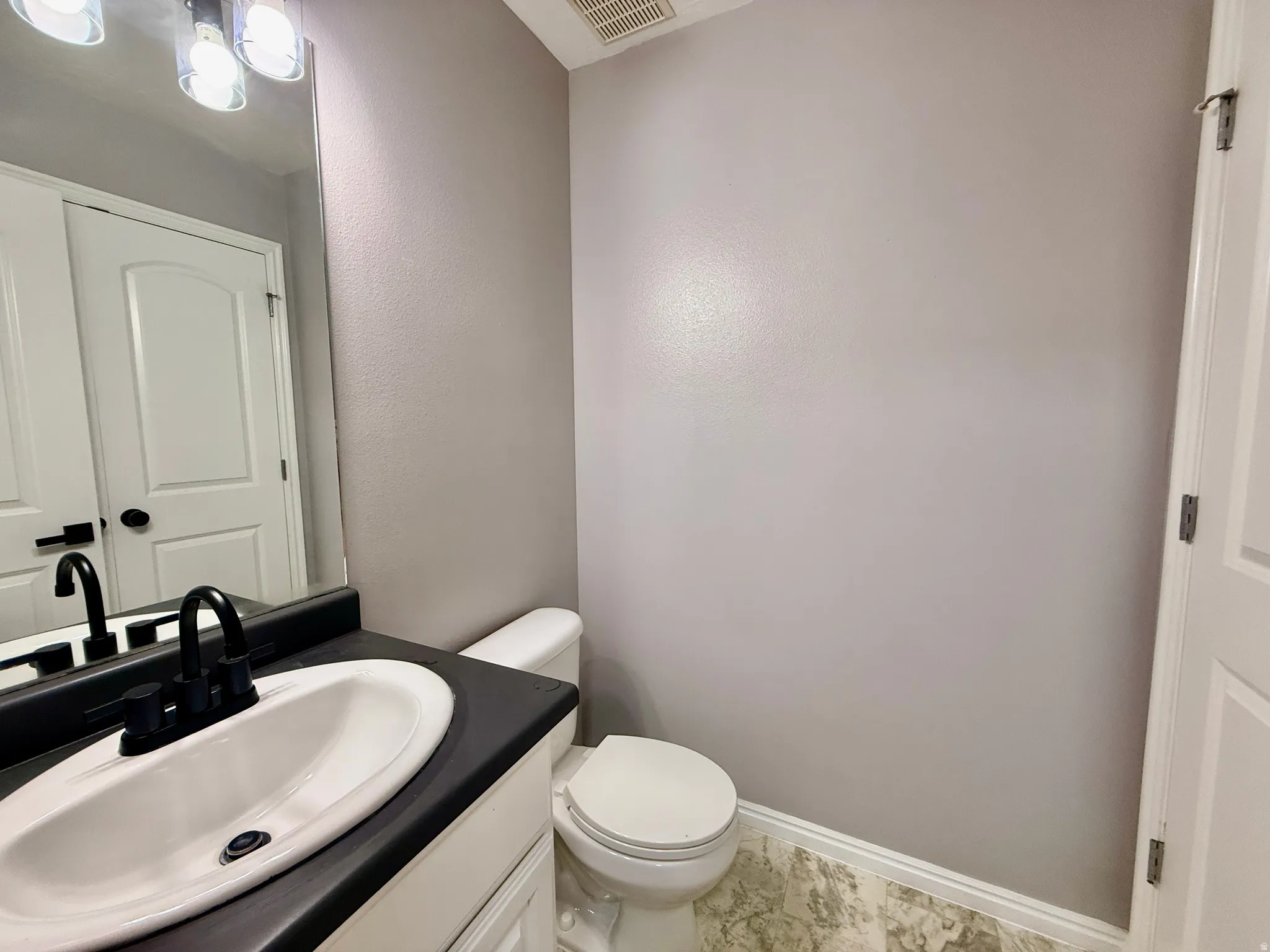 Bathroom featuring a white ceramic sink, dark countertop, matte black faucet, and a large wall-mounted mirror