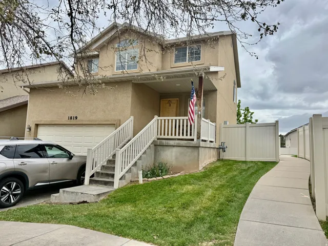 Traditional-style house featuring covered porch, stucco siding, and a garage