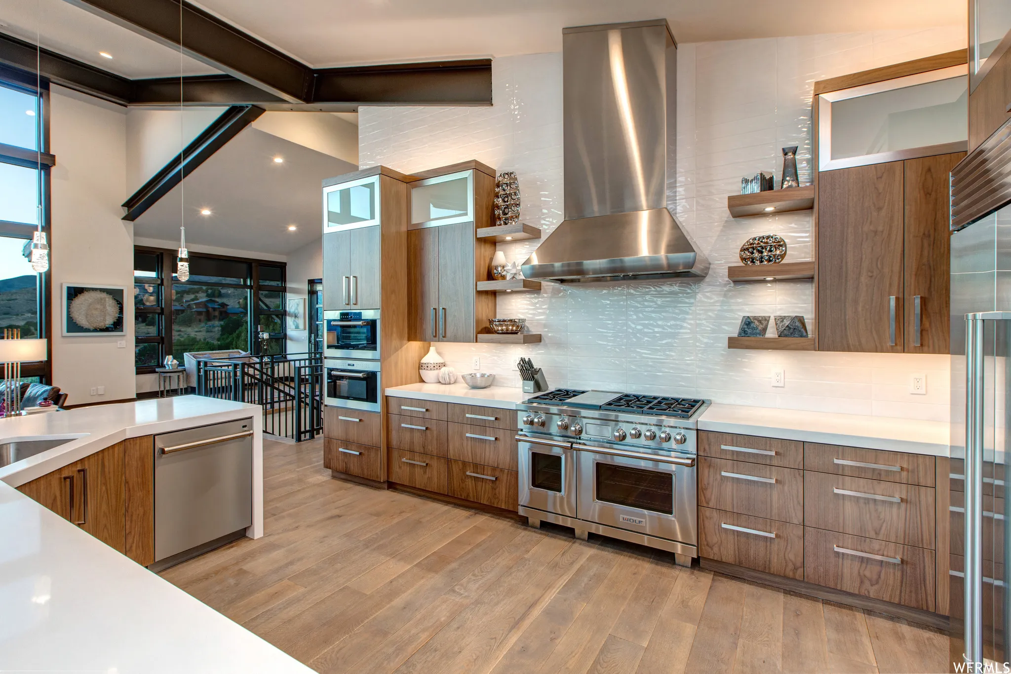 Kitchen with wood finish cabinets, range hood, modern cabinets, high end appliances, and light wood-type flooring