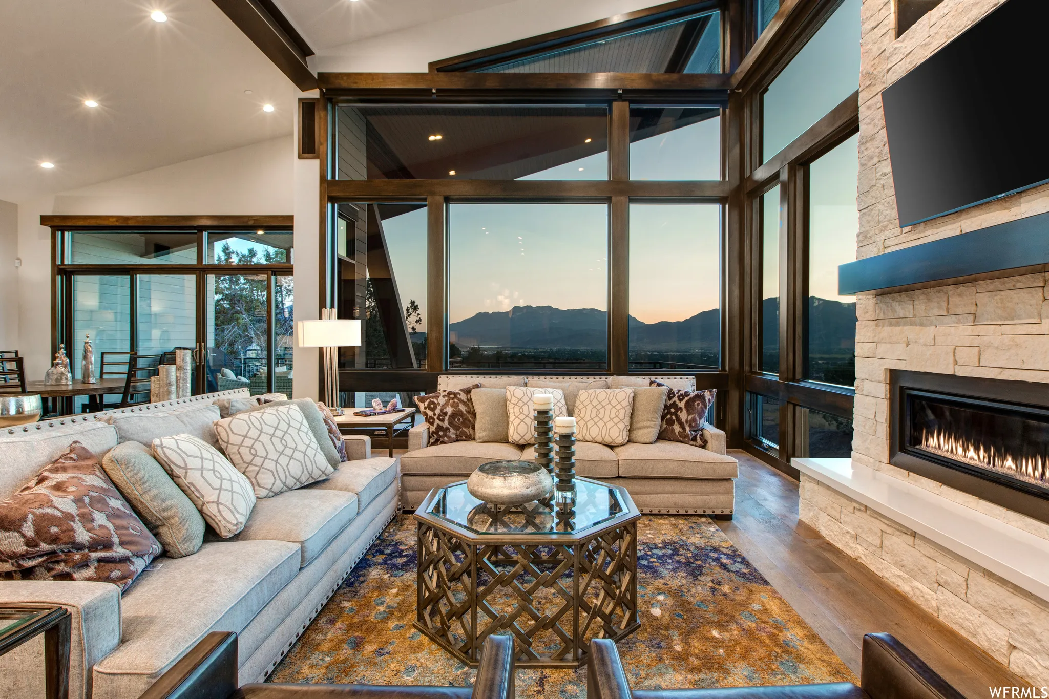 Living room featuring hardwood / wood-style flooring, a fireplace, vaulted ceiling, and floor to ceiling windows