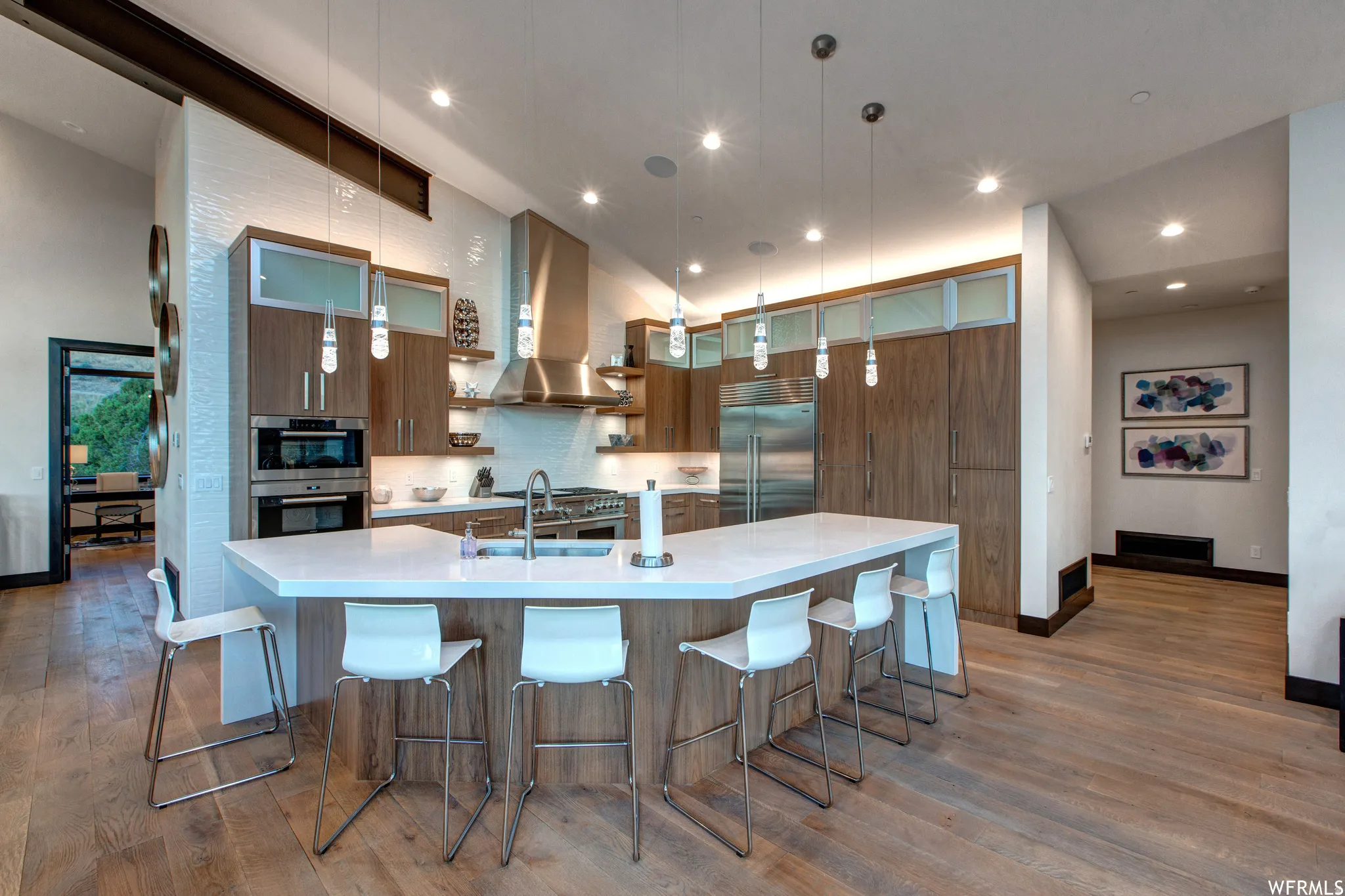 Kitchen with a kitchen bar, dark wood-style flooring, stainless steel appliances, open shelves, and light stone countertops