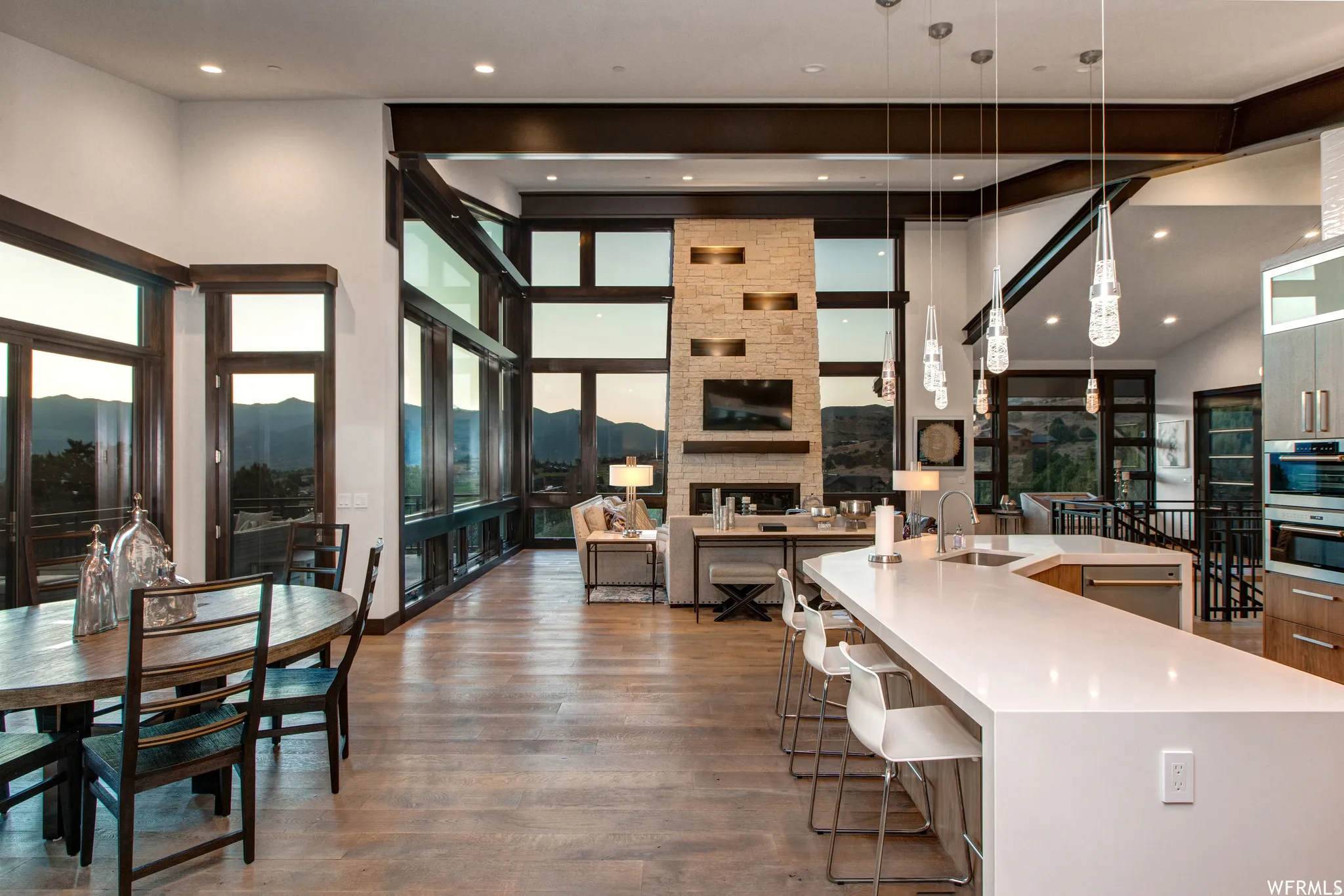 Kitchen featuring a kitchen breakfast bar, a stone fireplace, light stone counters, dark wood finished floors, and a high ceiling