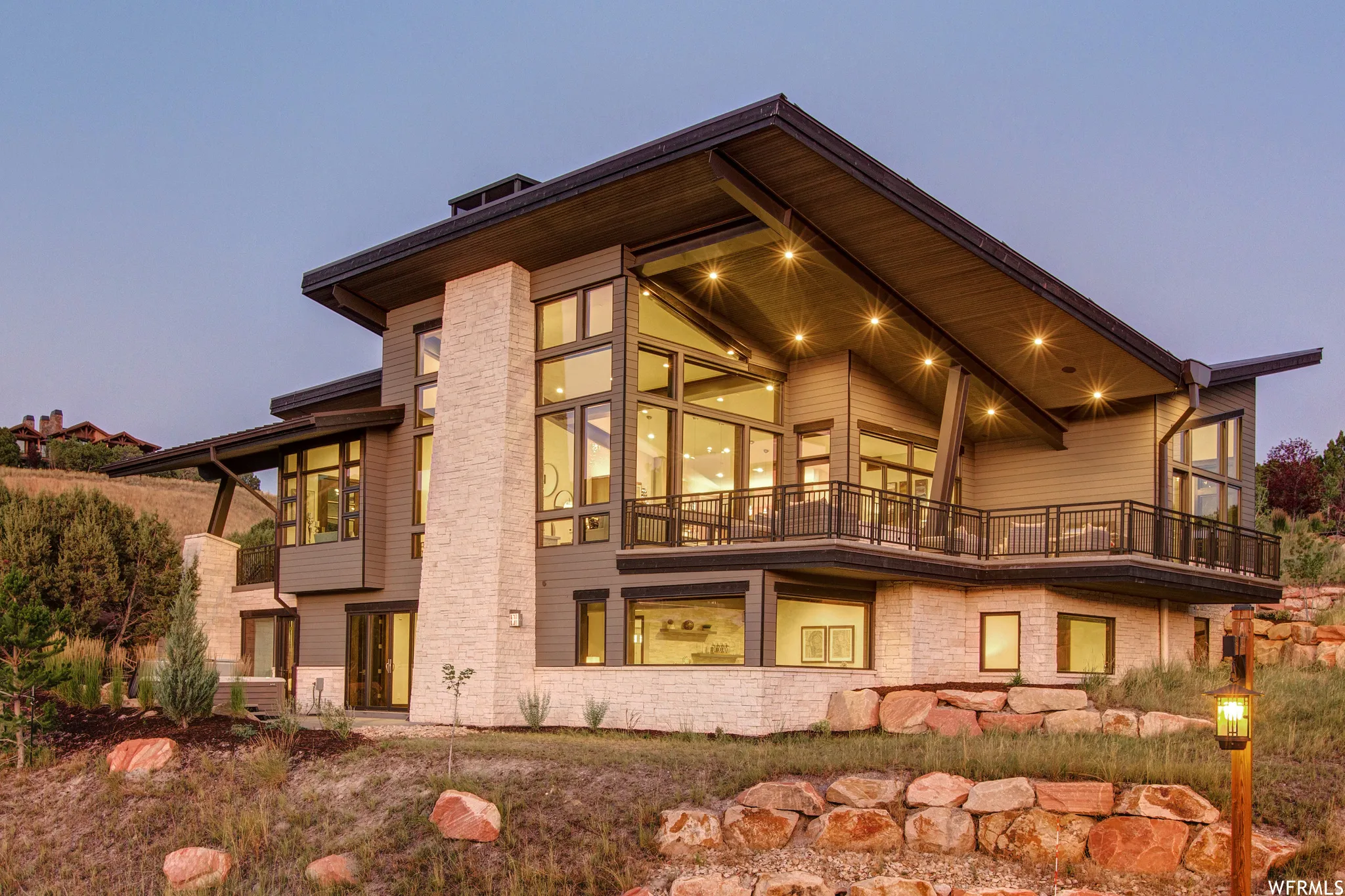 Back of house featuring a balcony and stone siding