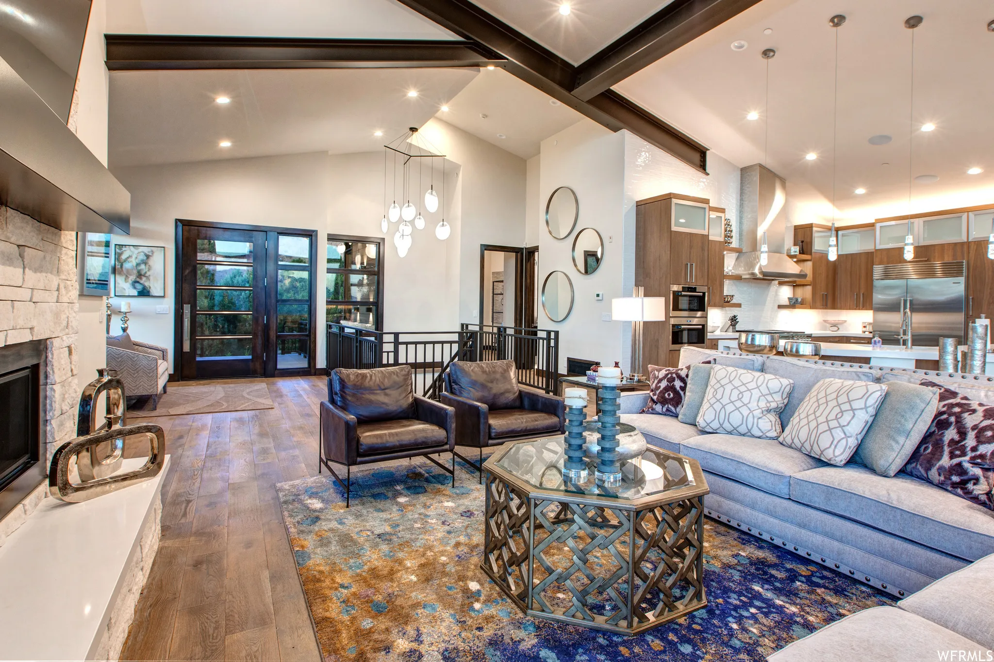 Living room with dark wood-style flooring, lofted ceiling, a stone fireplace, and hanging lights