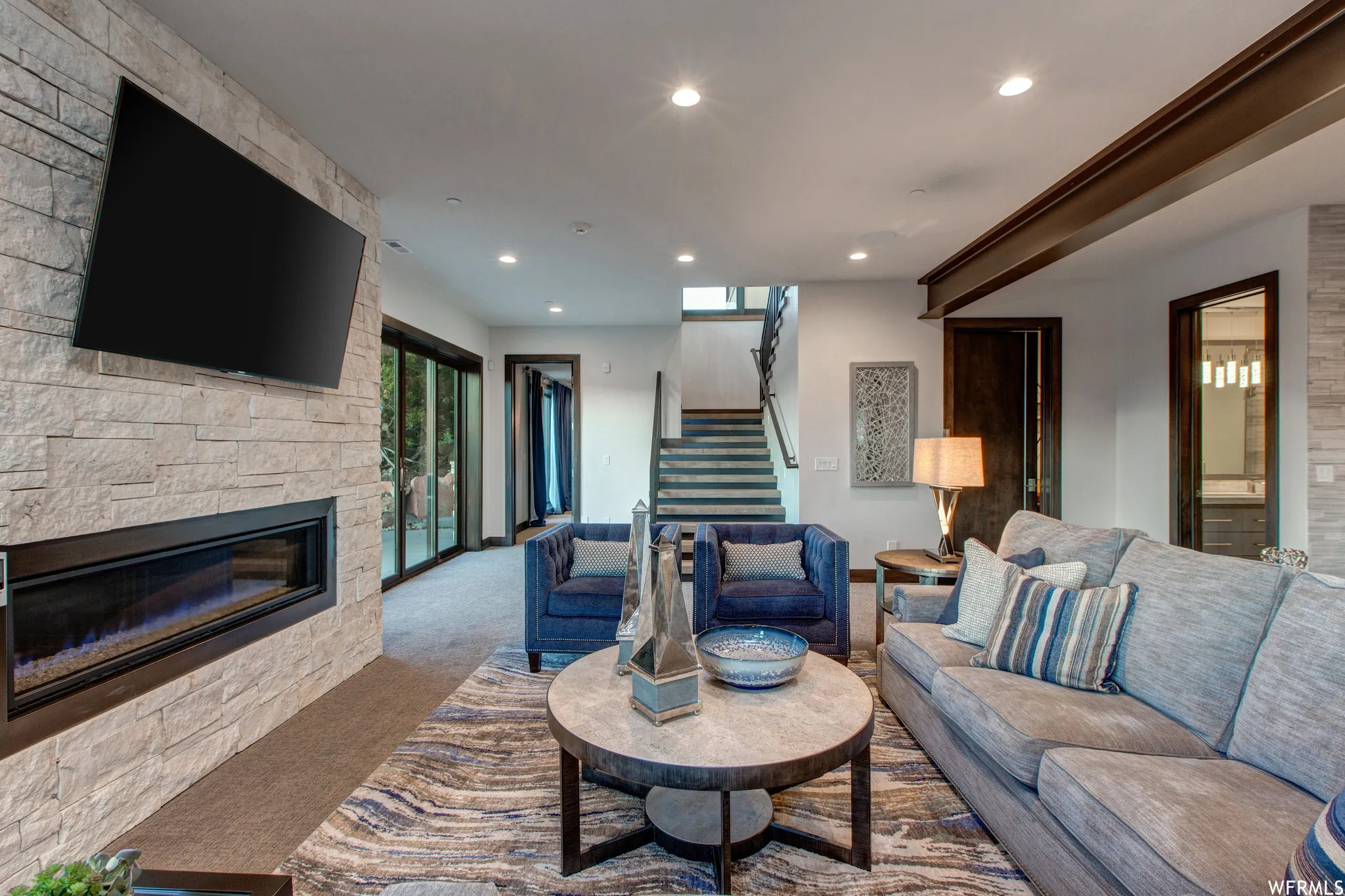 Living room with carpet flooring, recessed lighting, and a stone fireplace