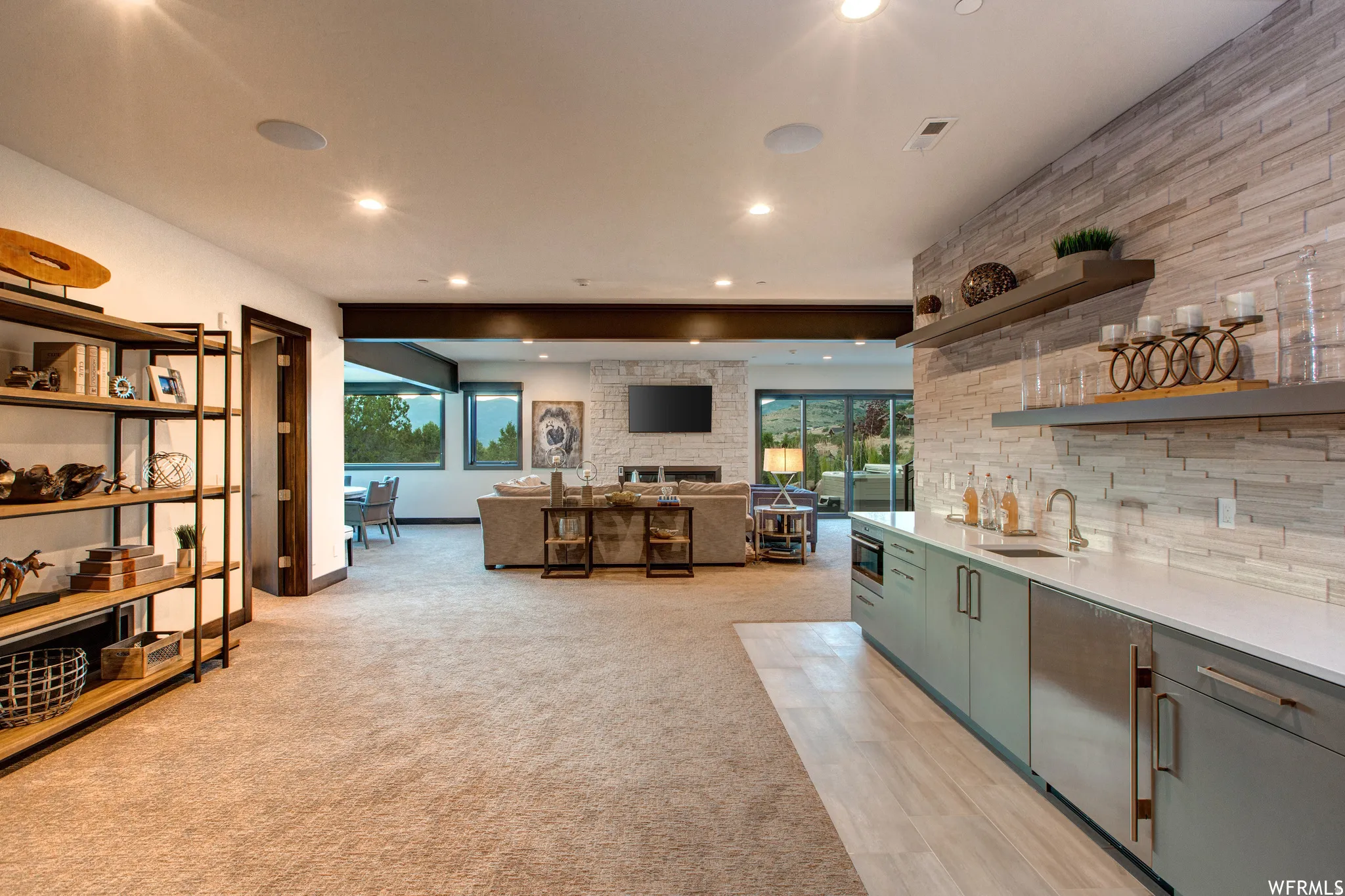 Kitchen featuring open shelves, open floor plan, light colored carpet, recessed lighting, and light stone countertops